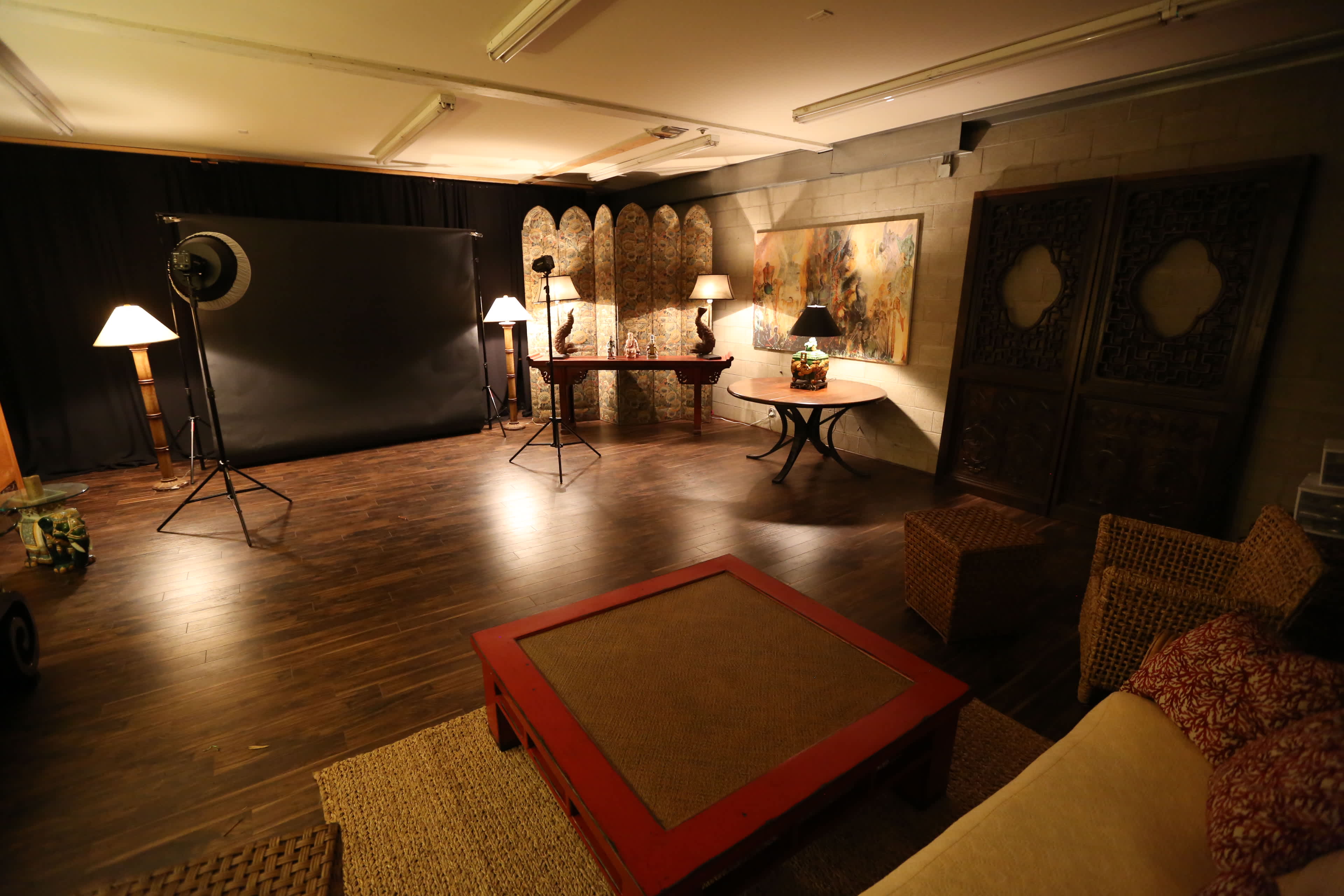 A spacious studio setting with a large backdrop, lighting equipment, and various pieces of furniture arranged for photography.