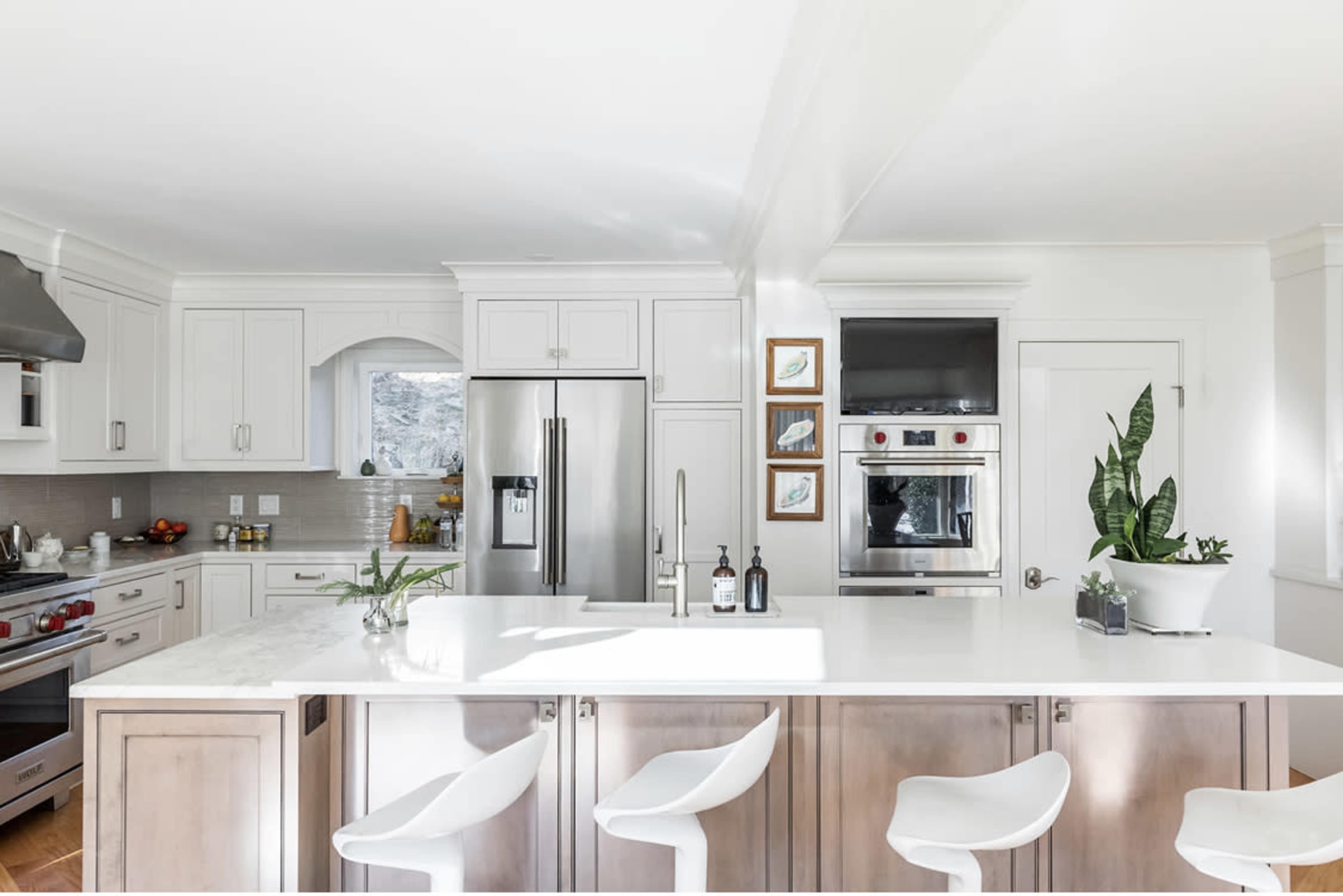 The kitchen features modern appliances, a white marble countertop with bar seating, and light-colored cabinetry.