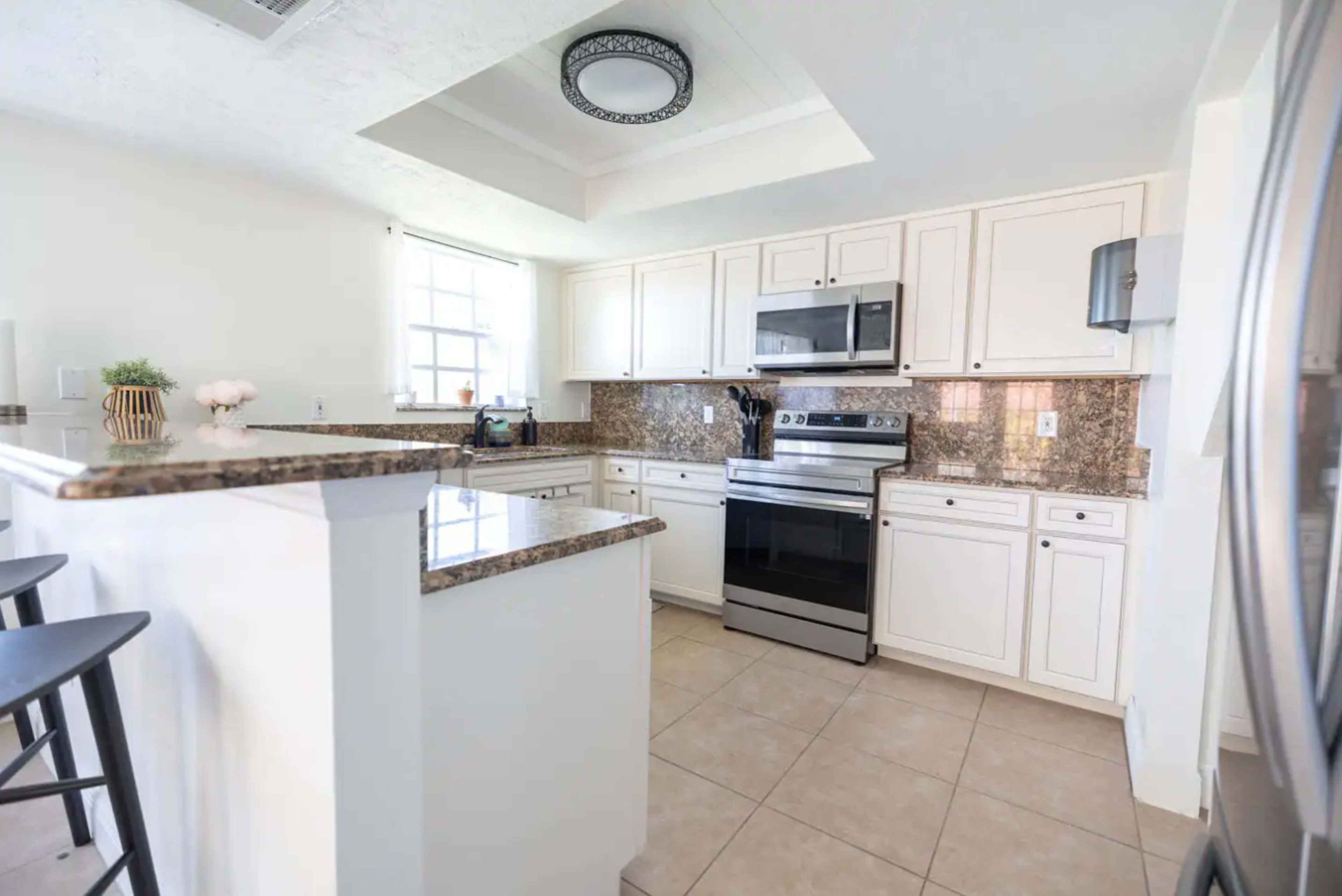 A modern kitchen features white cabinetry, stainless steel appliances, and granite countertops.