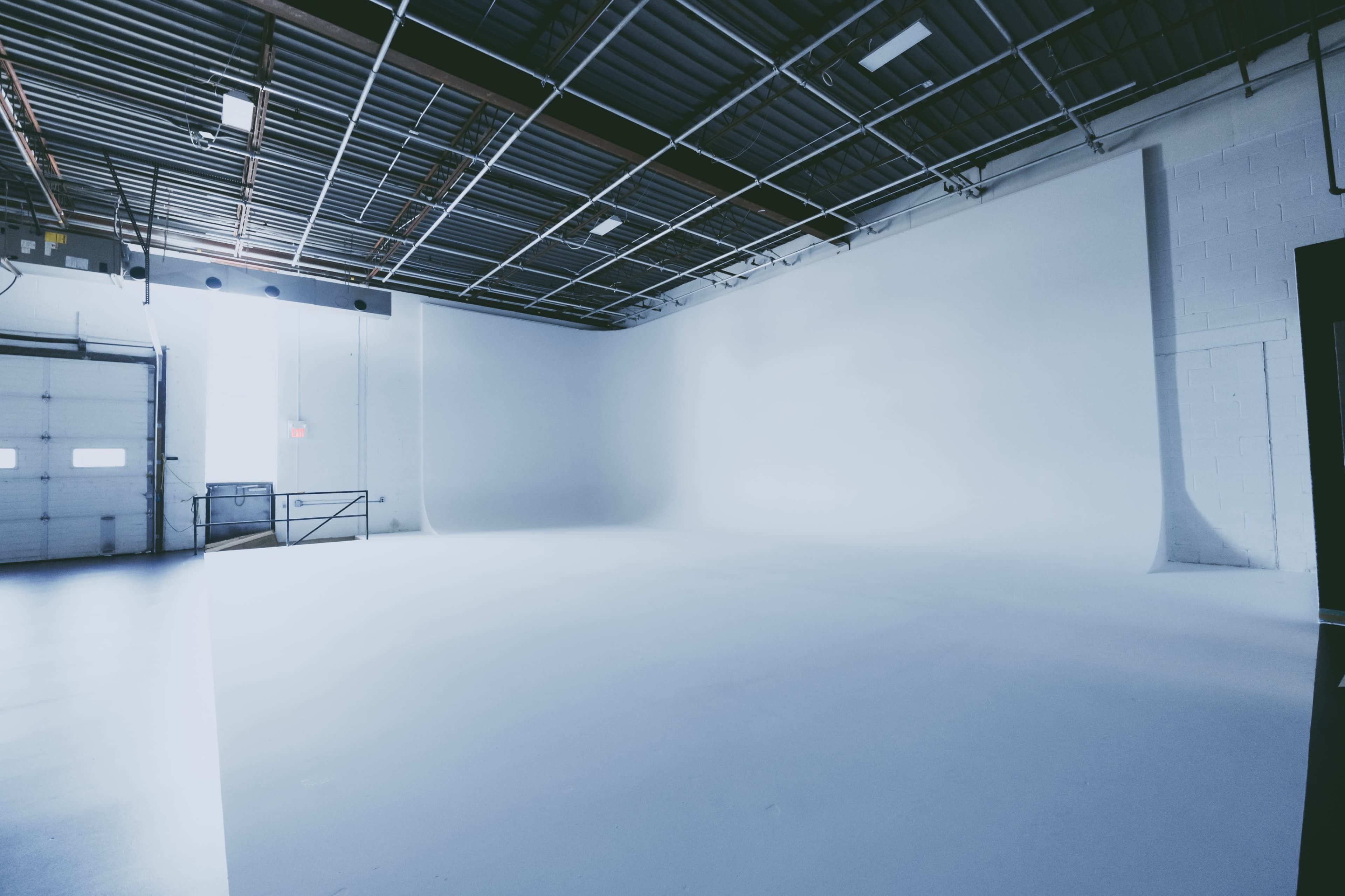 An empty photo studio with a large white background and high ceilings.