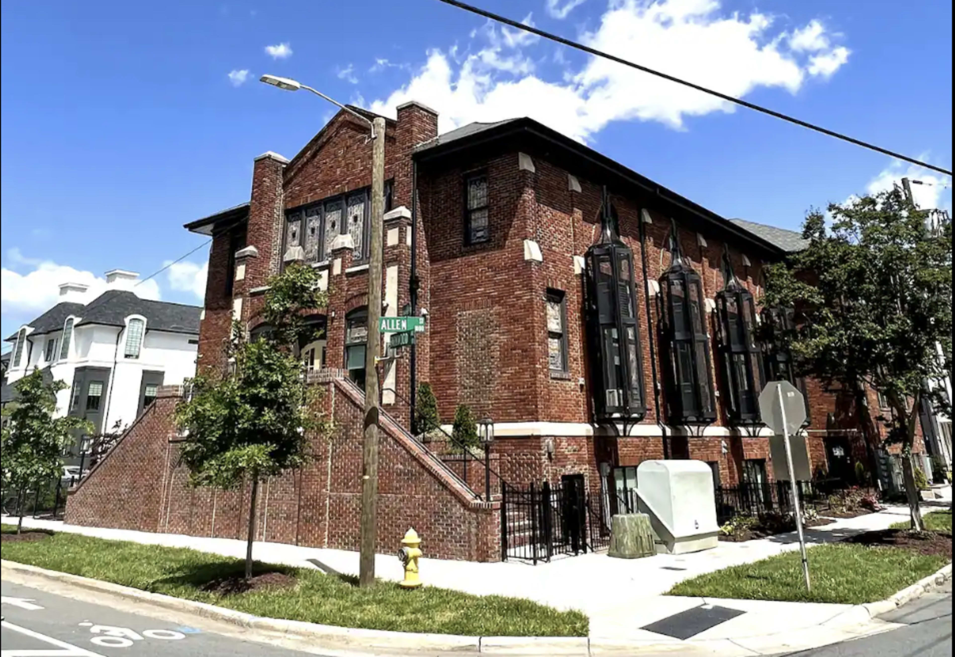 A brick building with large windows and a distinct architectural style is situated at the corner of Allen Street.