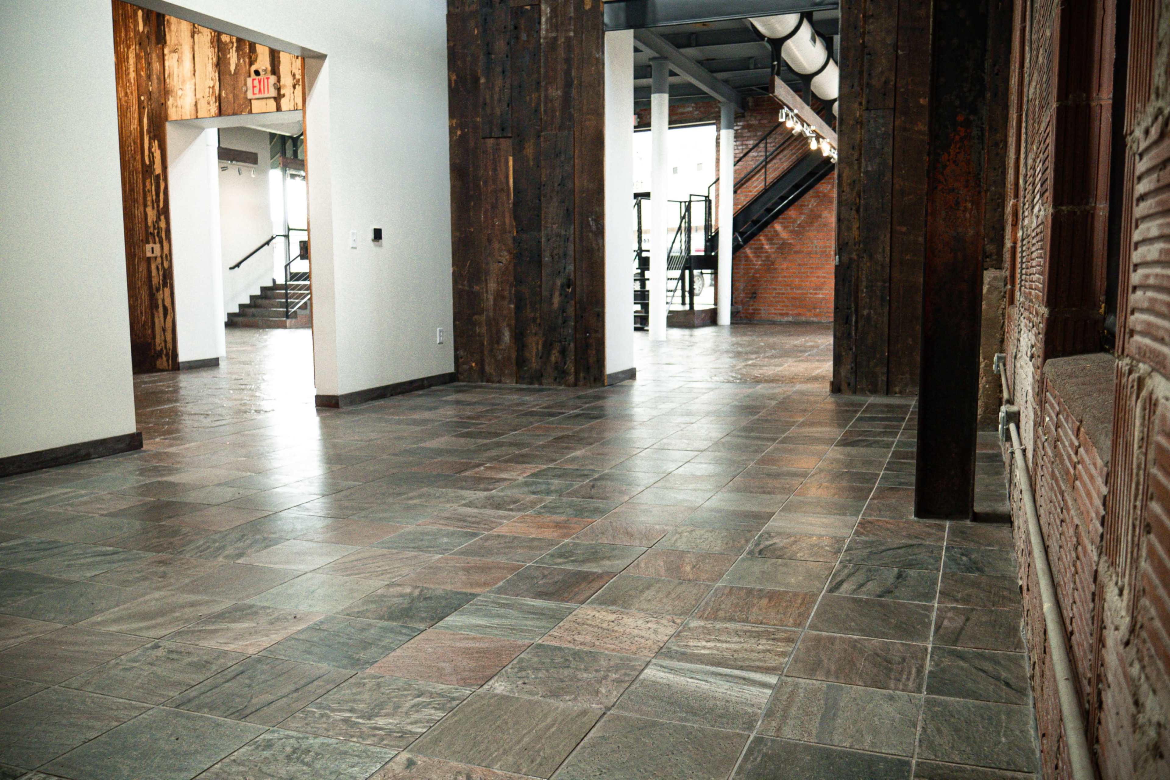 The image shows a spacious interior hallway featuring tiled flooring, wooden accents, and multiple doorways leading to different areas.