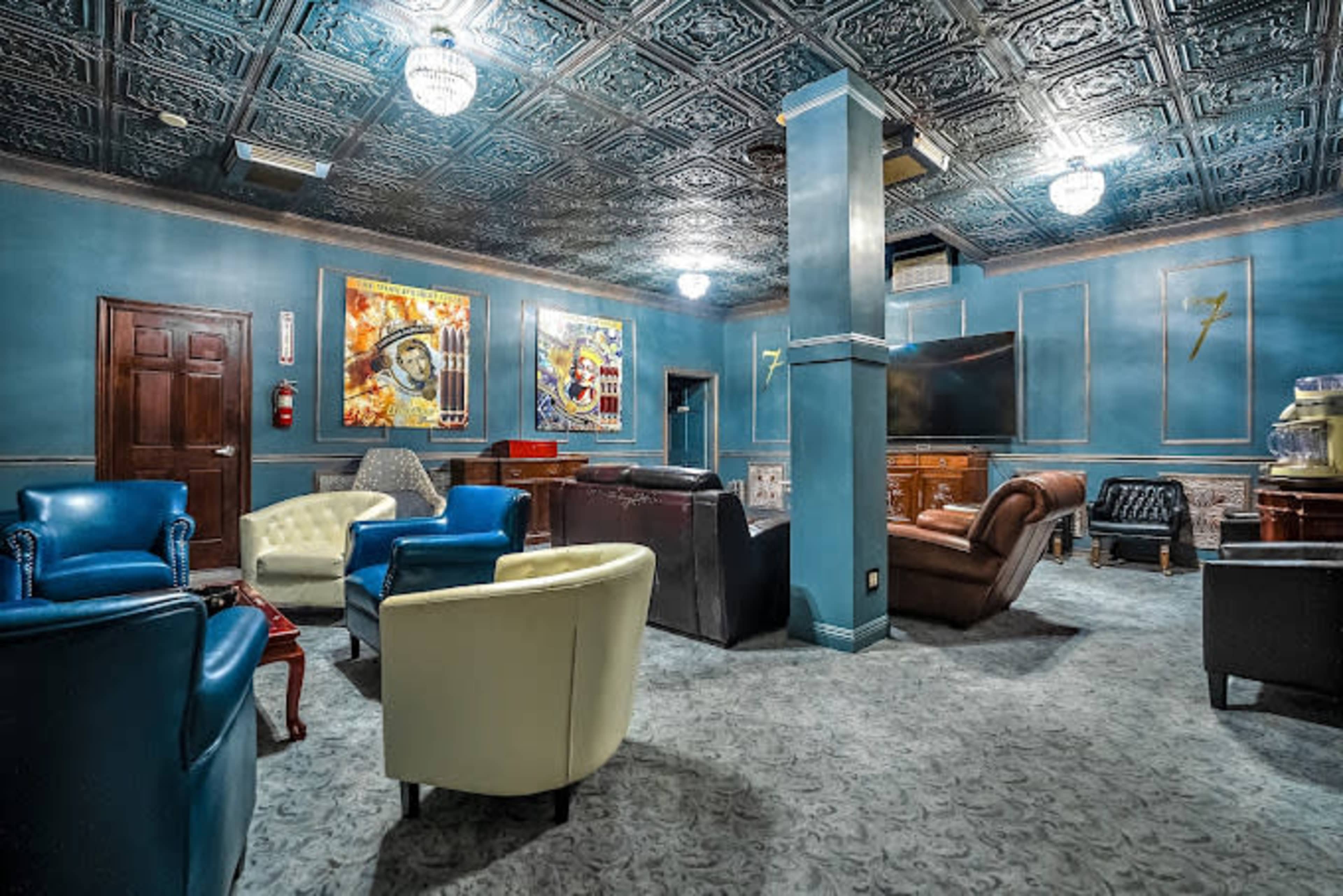 The image shows a lounge area with several upholstered chairs, a television, and artwork on the walls.