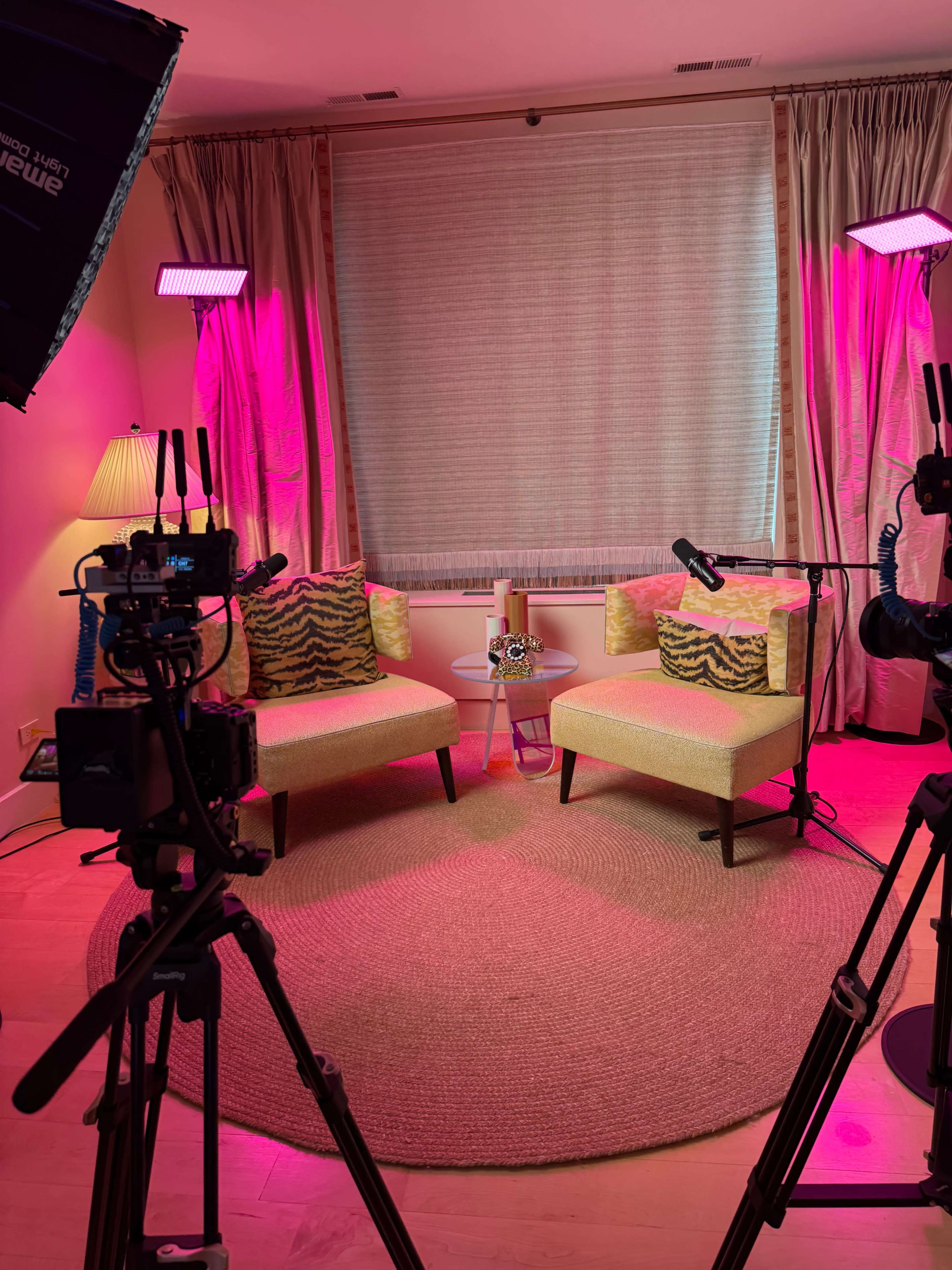 A cozy set with two chairs and vibrant lighting, arranged for a video shoot.