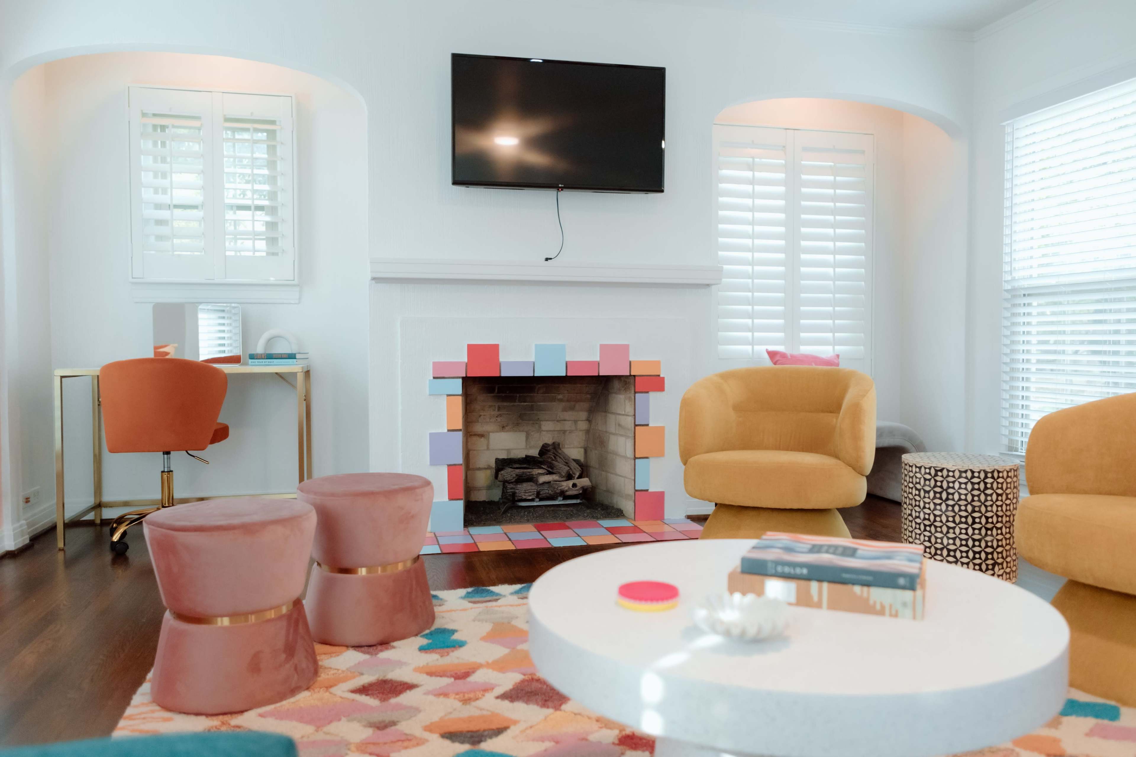 A cozy living room features a brick fireplace adorned with colorful blocks, comfortable seating, and a wall-mounted television.