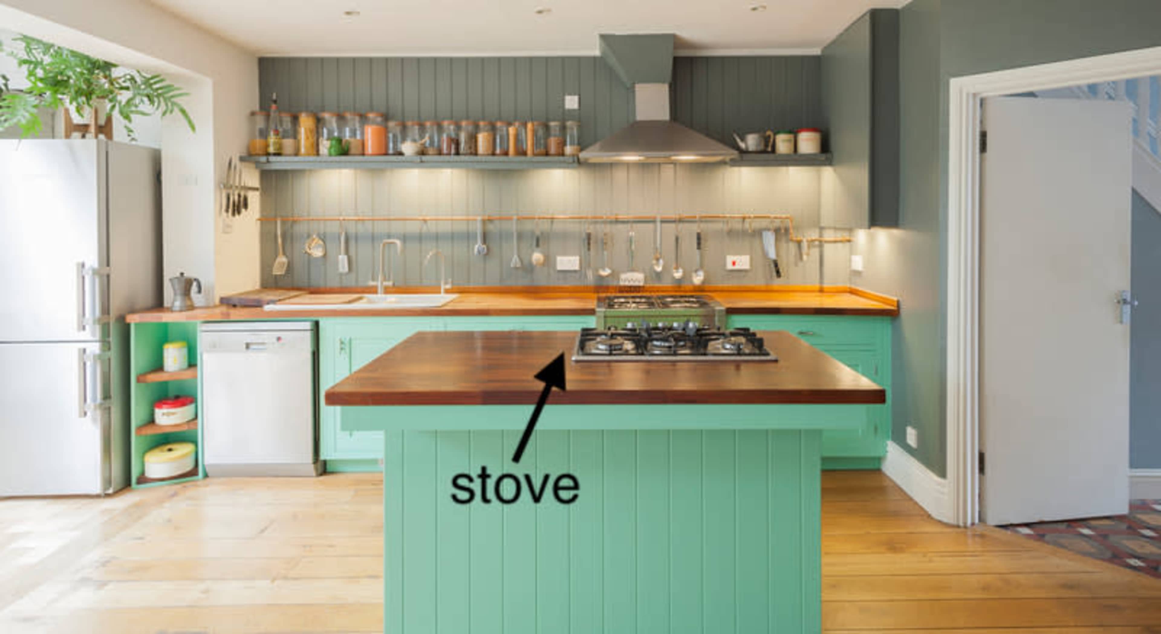 A modern kitchen with a green island featuring a gas stove, stainless steel appliances, and wooden countertops.