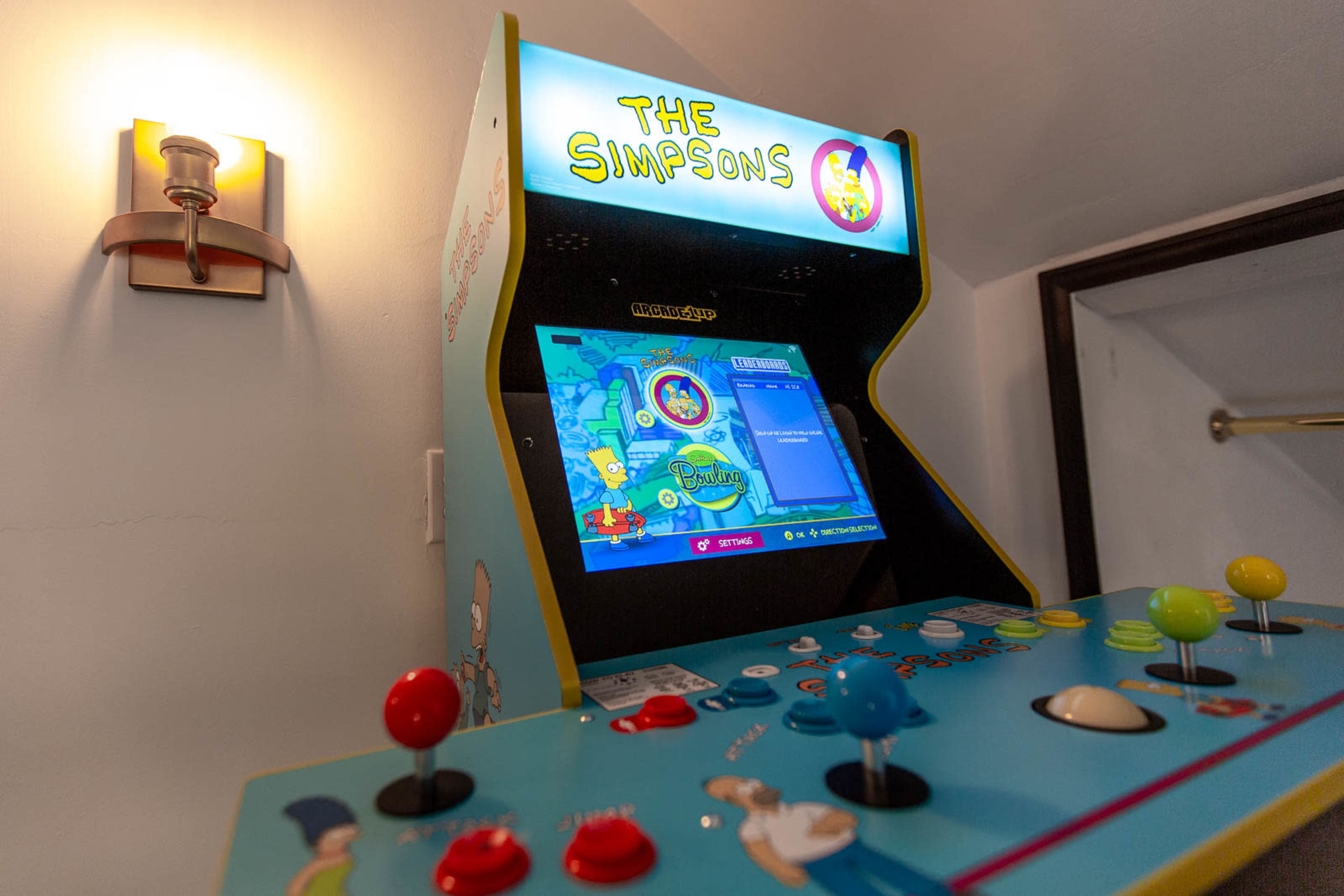 A retro arcade cabinet featuring "The Simpsons" video game, with colorful buttons and a vibrant display.