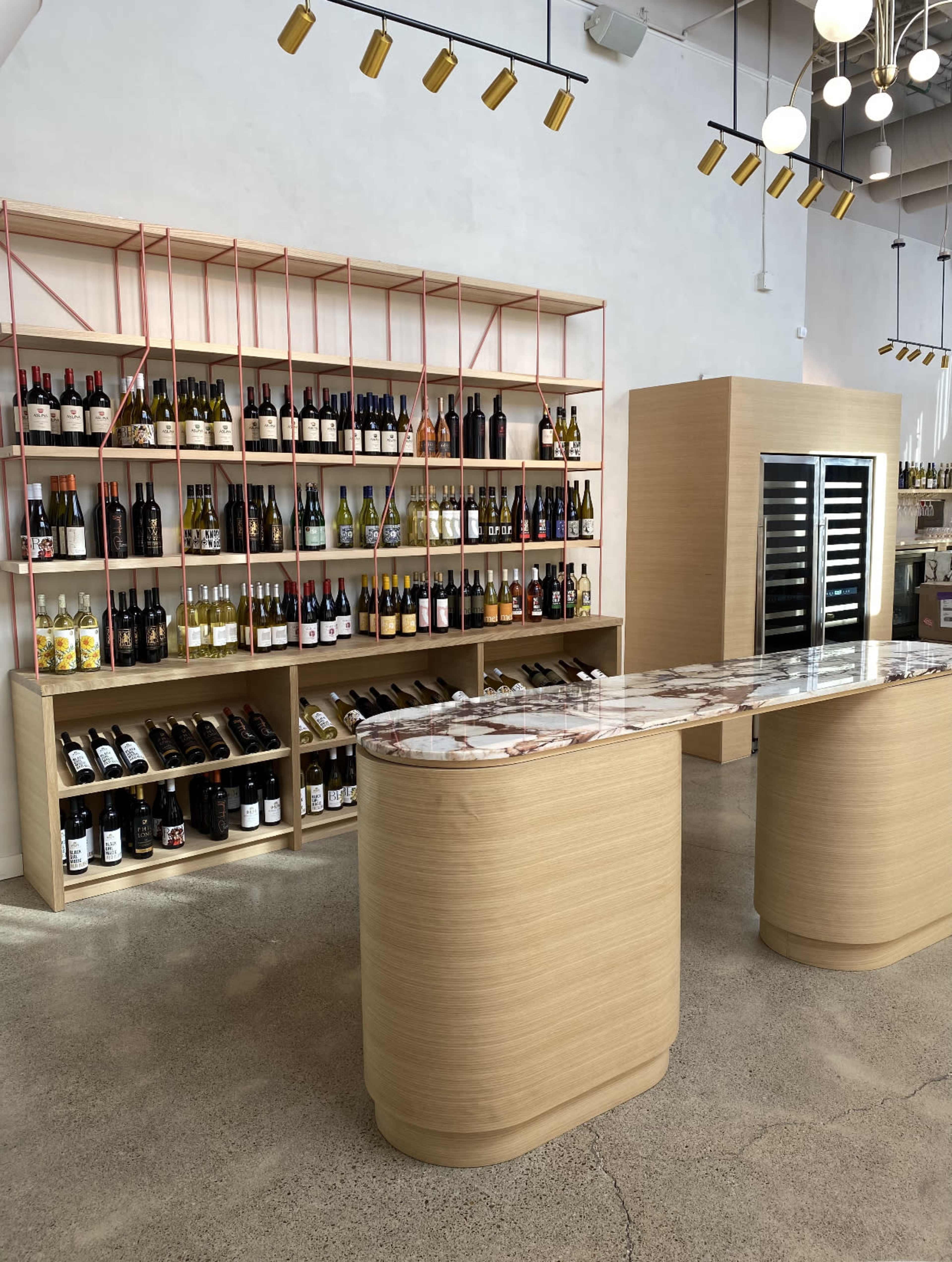 A modern wine shop interior with a curved counter and shelves lined with various bottles of wine.