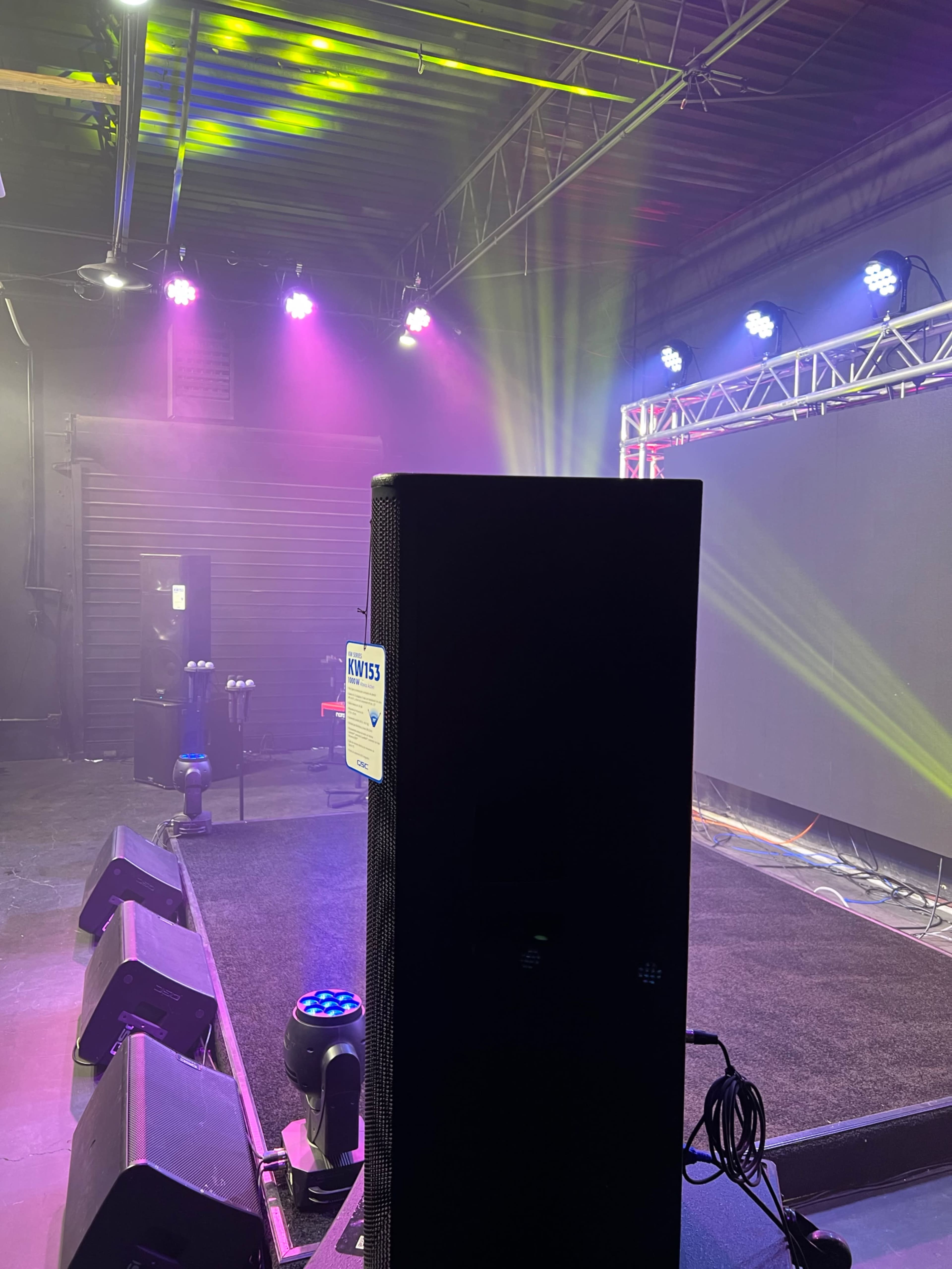 A stage setup with speakers, lighting, and a large screen in the background.