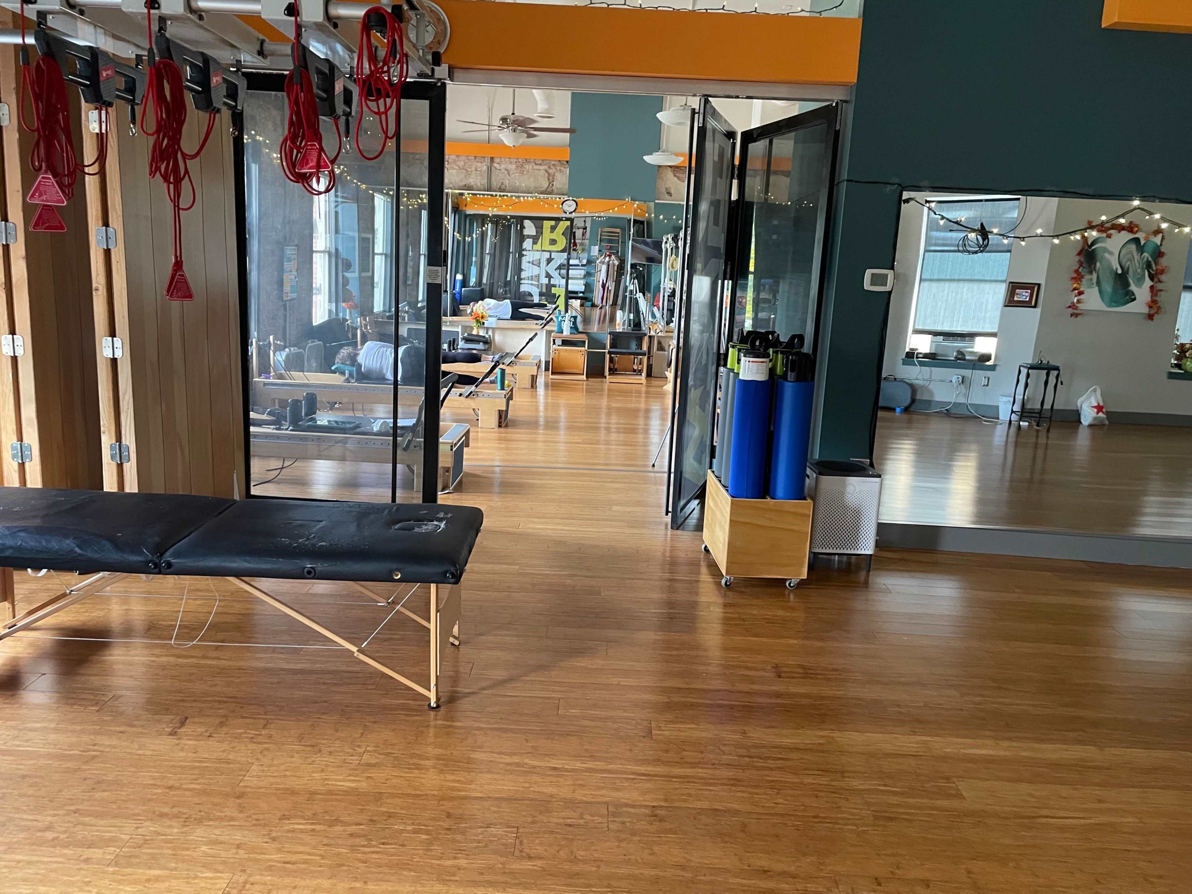 An interior space of a fitness studio featuring exercise equipment, treatment tables, and mirrored walls.