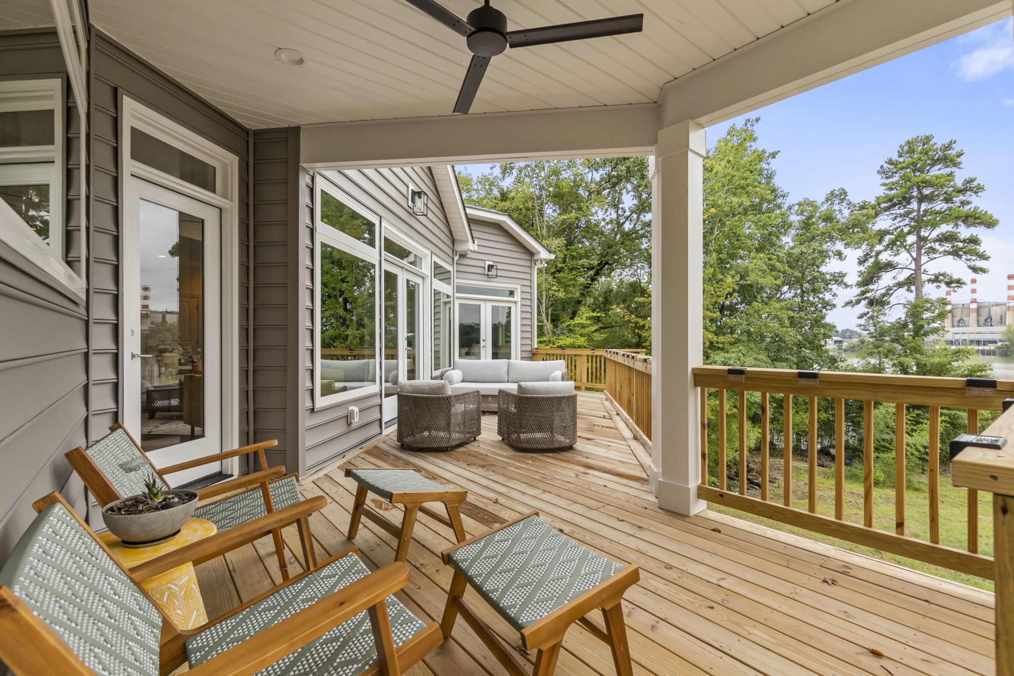 A spacious wooden deck with seating areas surrounded by trees and a view of a landscape.