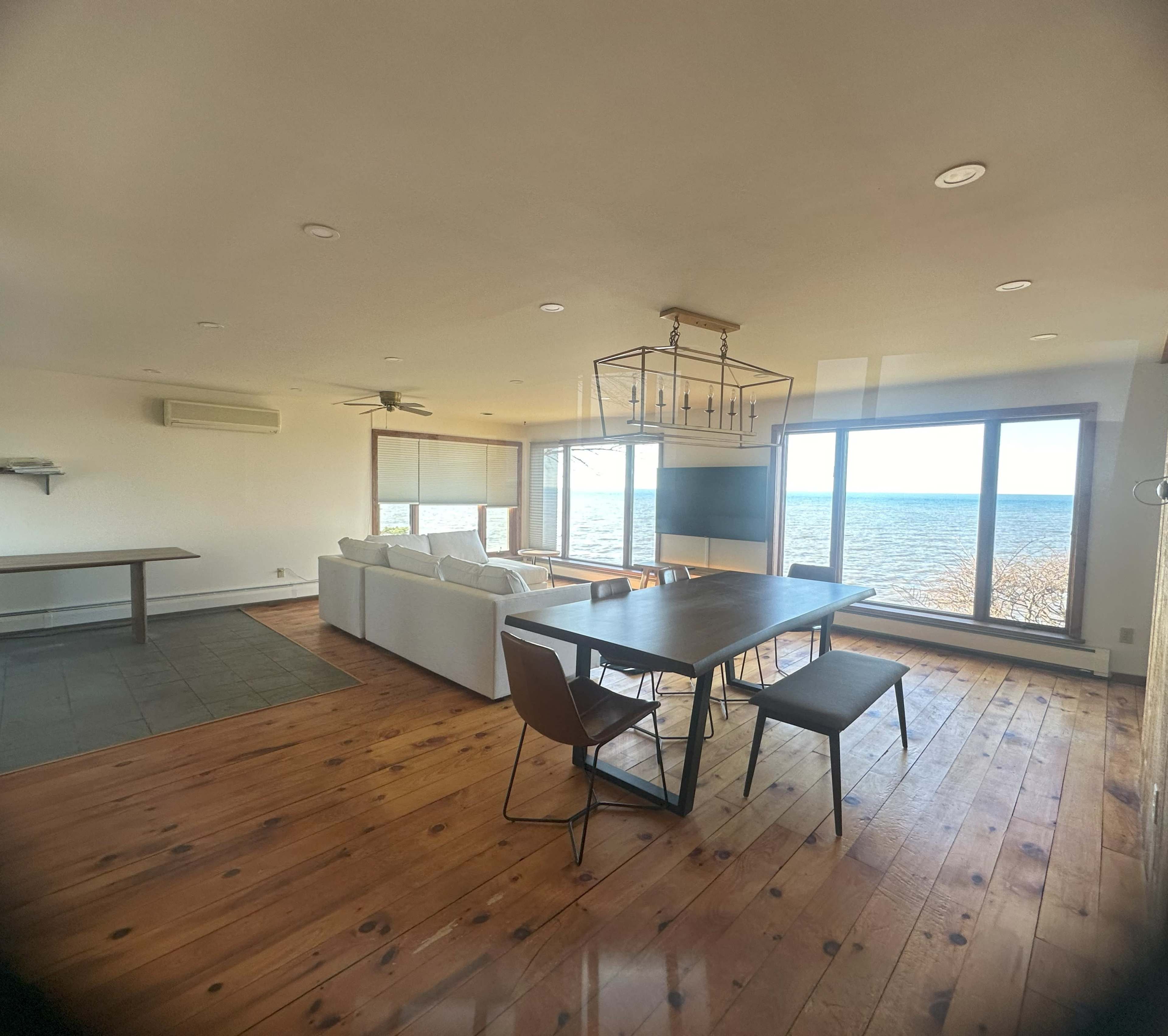 A stylish open-concept living and dining area with a large window overlooking a body of water.