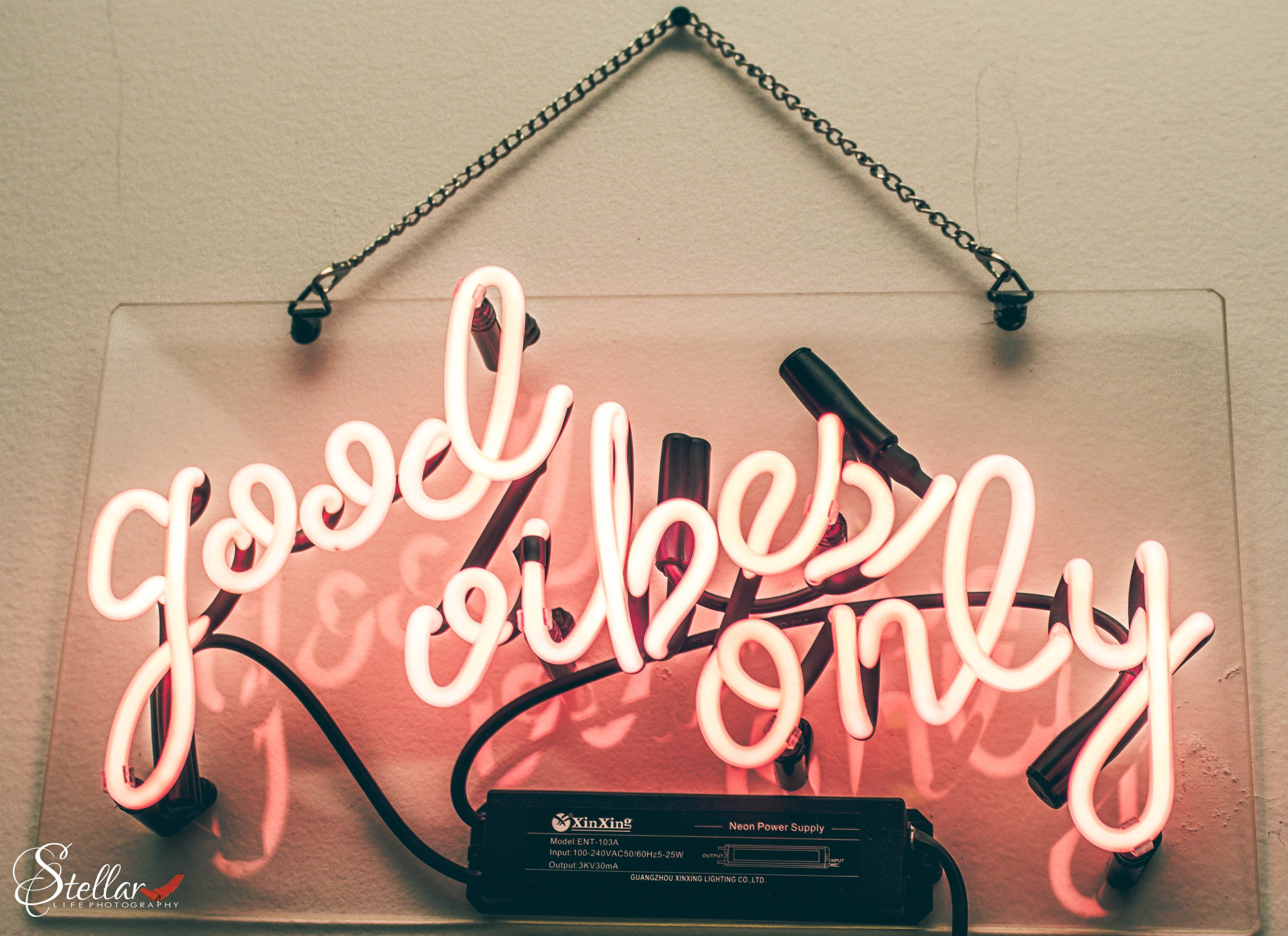 A neon sign that reads "good vibes only" in pink and white lettering, mounted on a wall.