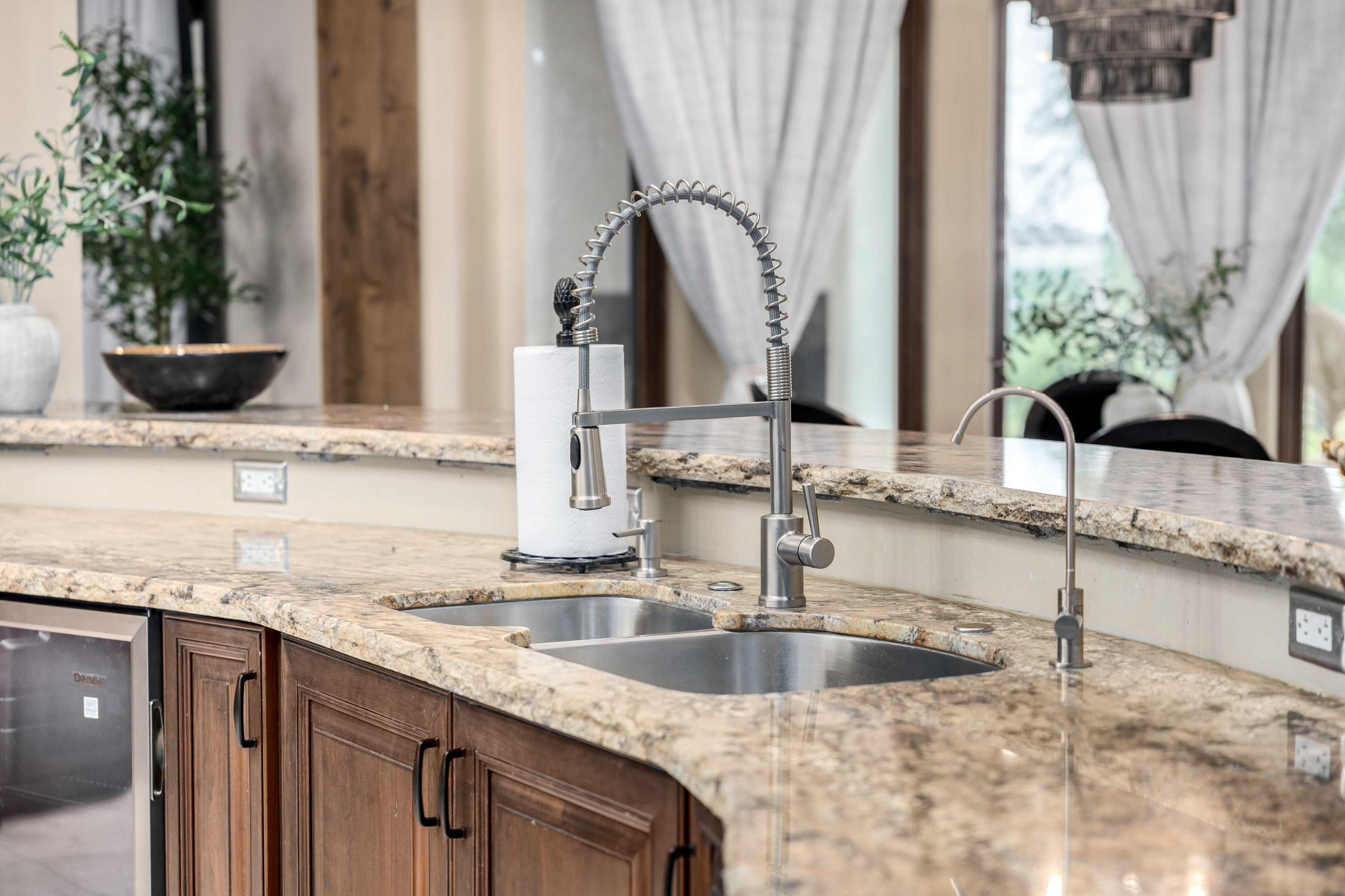 A modern kitchen features a granite countertop with a double sink and a tall, stylish faucet.