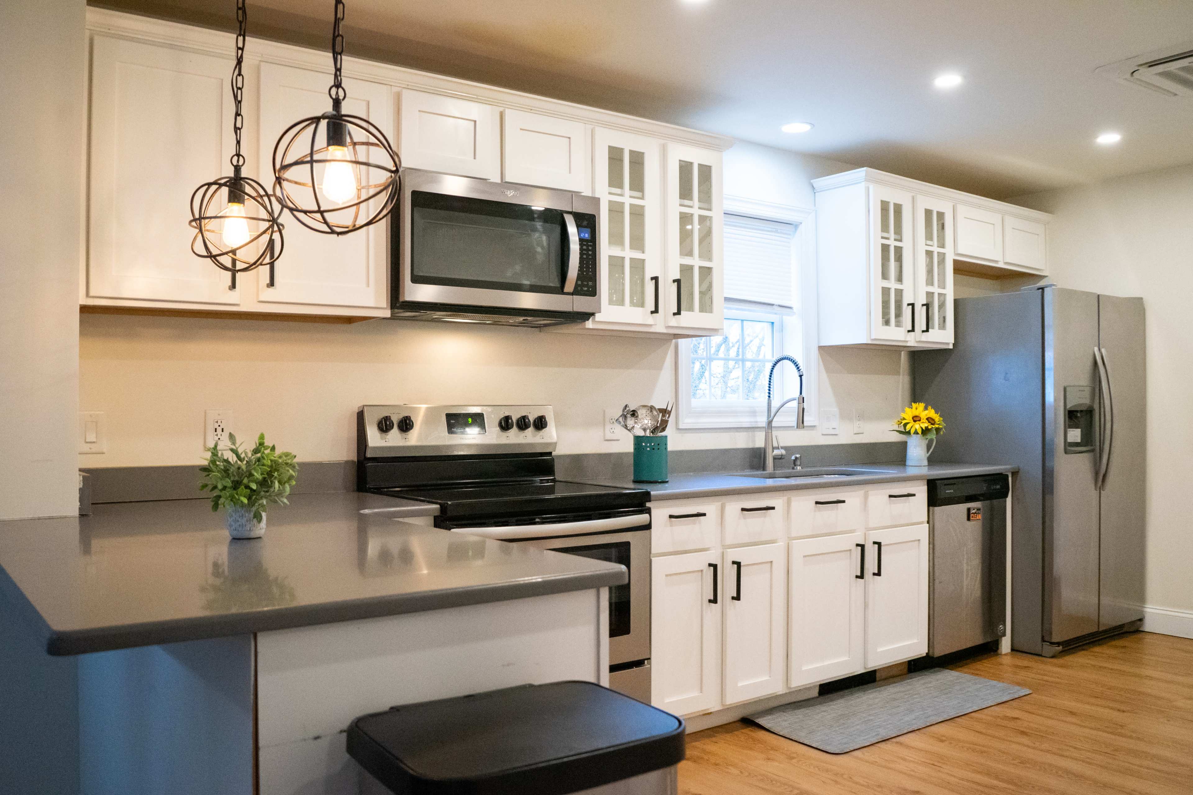 A modern kitchen featuring white cabinets, stainless steel appliances, and a gray countertop.