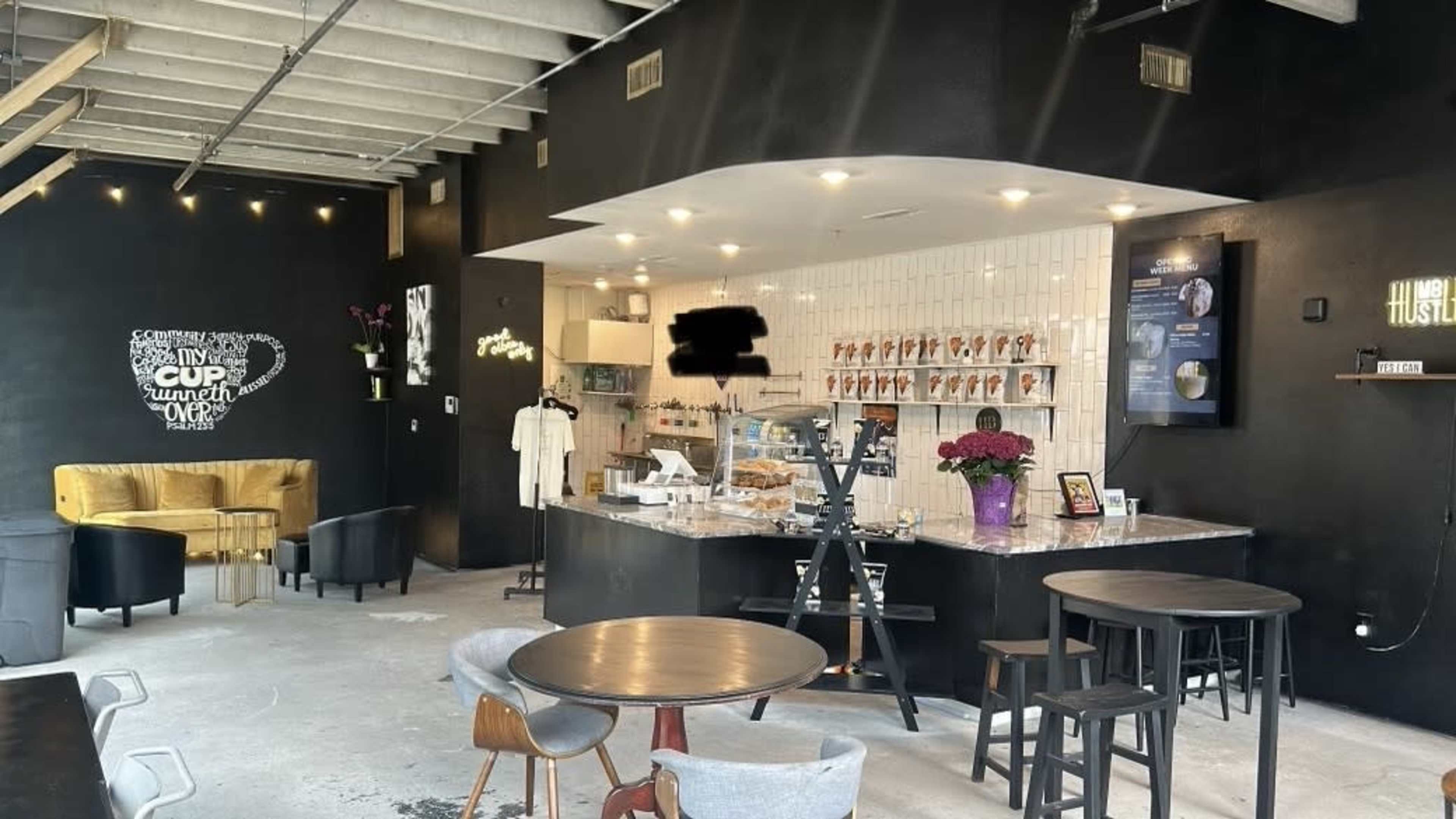 A modern café interior with a black and white color scheme, featuring a service counter, tables, and various seating arrangements.