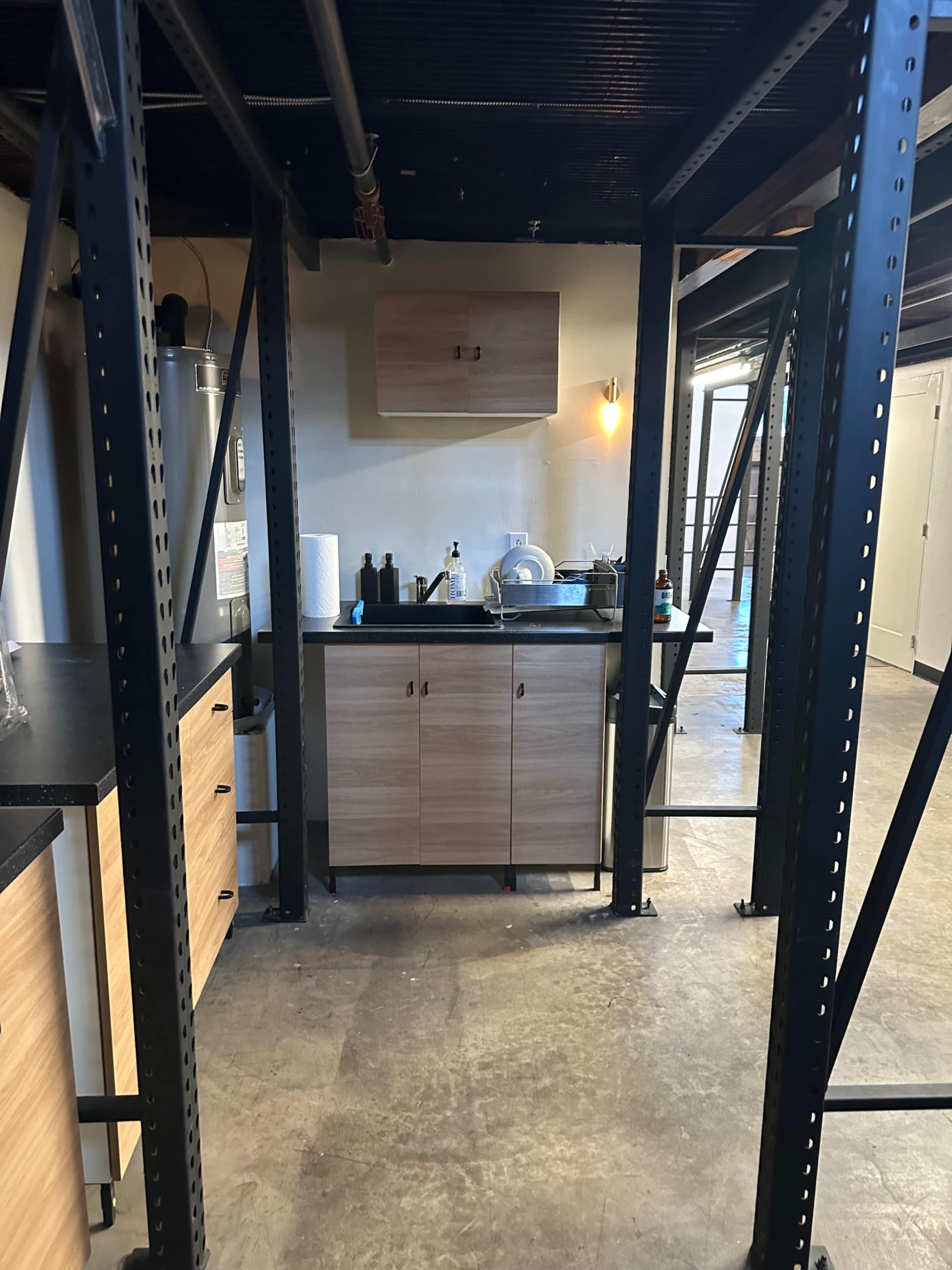 A kitchen area with wood cabinets and a countertop, supported by metal shelving structures.