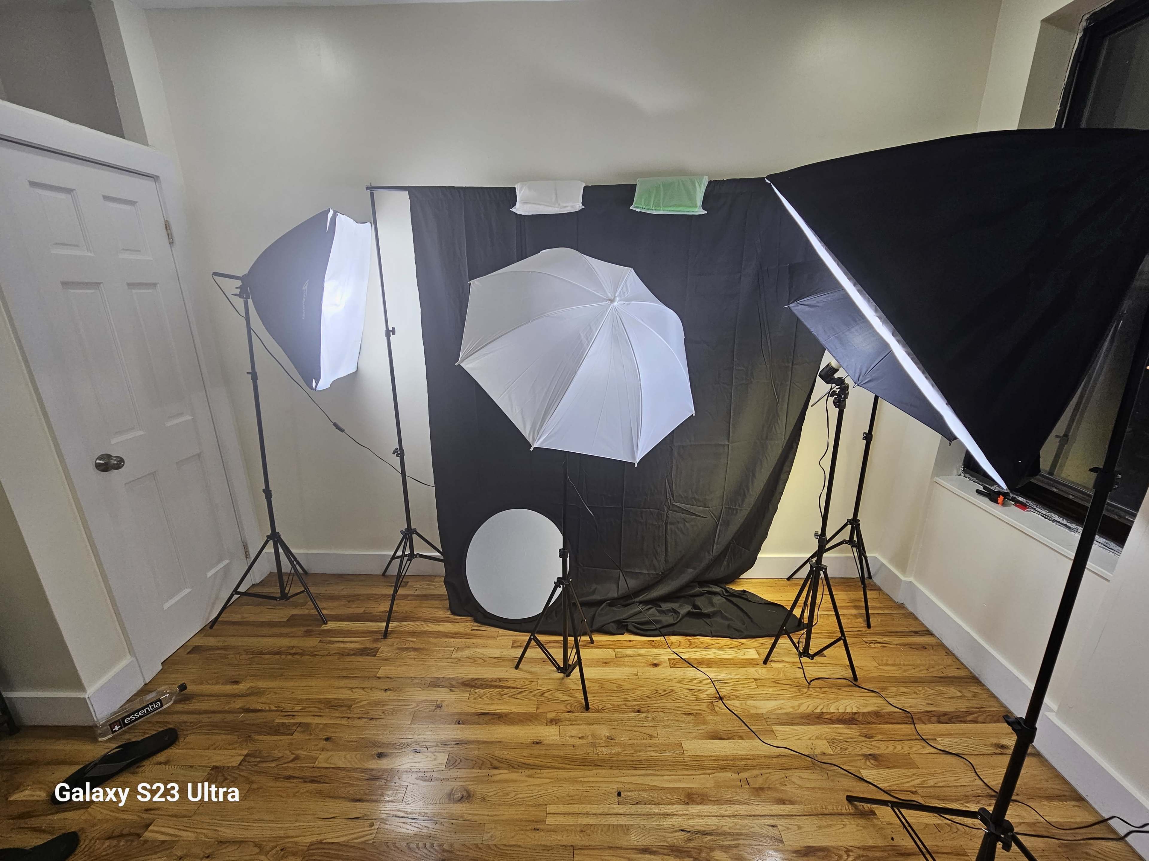 A well-lit photography setup featuring two softbox lights, a round reflector, and a black background.