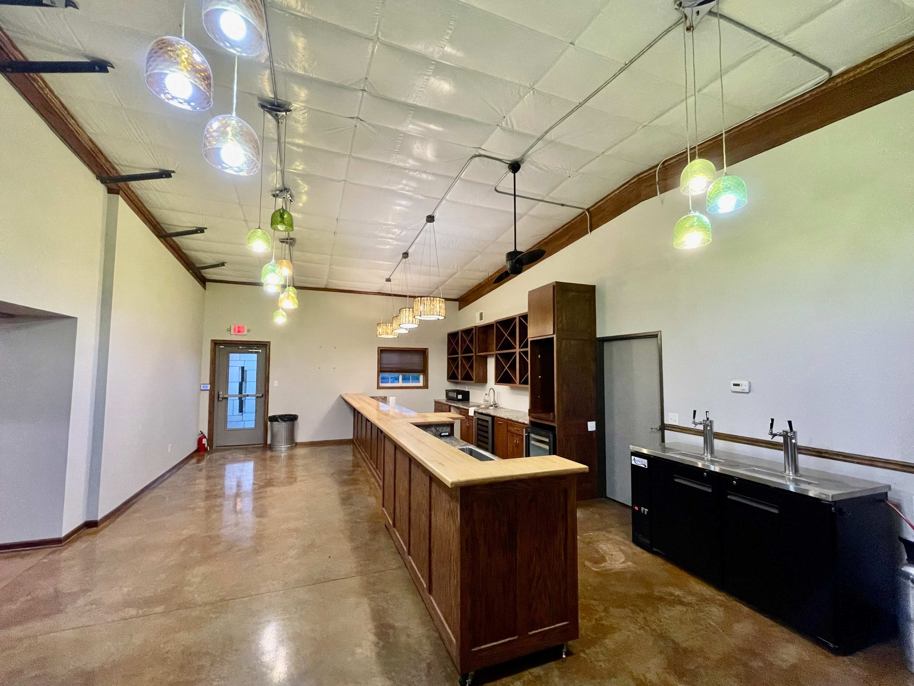 A spacious kitchen with a wooden counter, dark cabinetry, and hanging pendant lights, featuring stainless steel appliances along one wall.