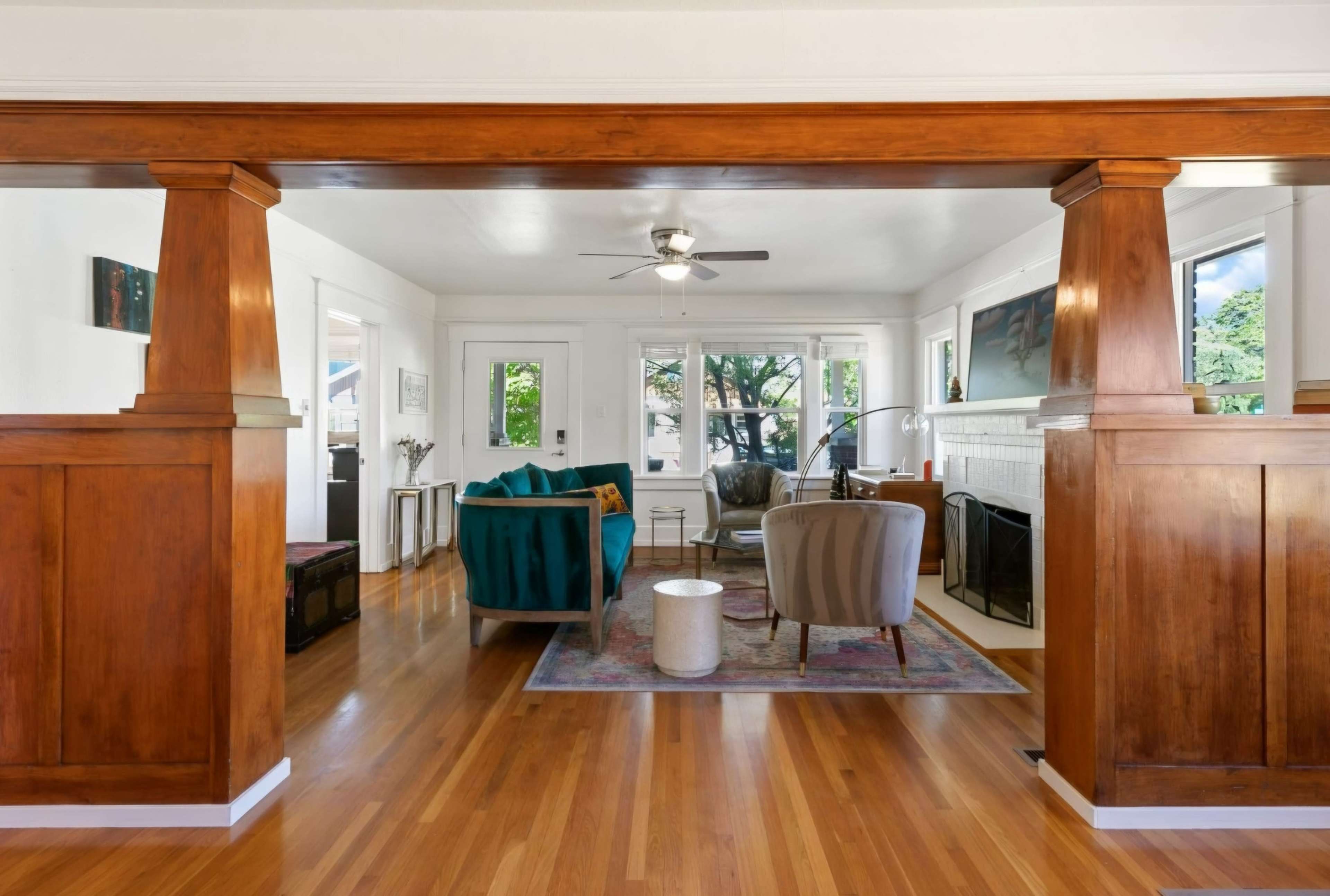 A spacious living room with a mix of seating options, large windows letting in natural light, and wooden details in the architecture.