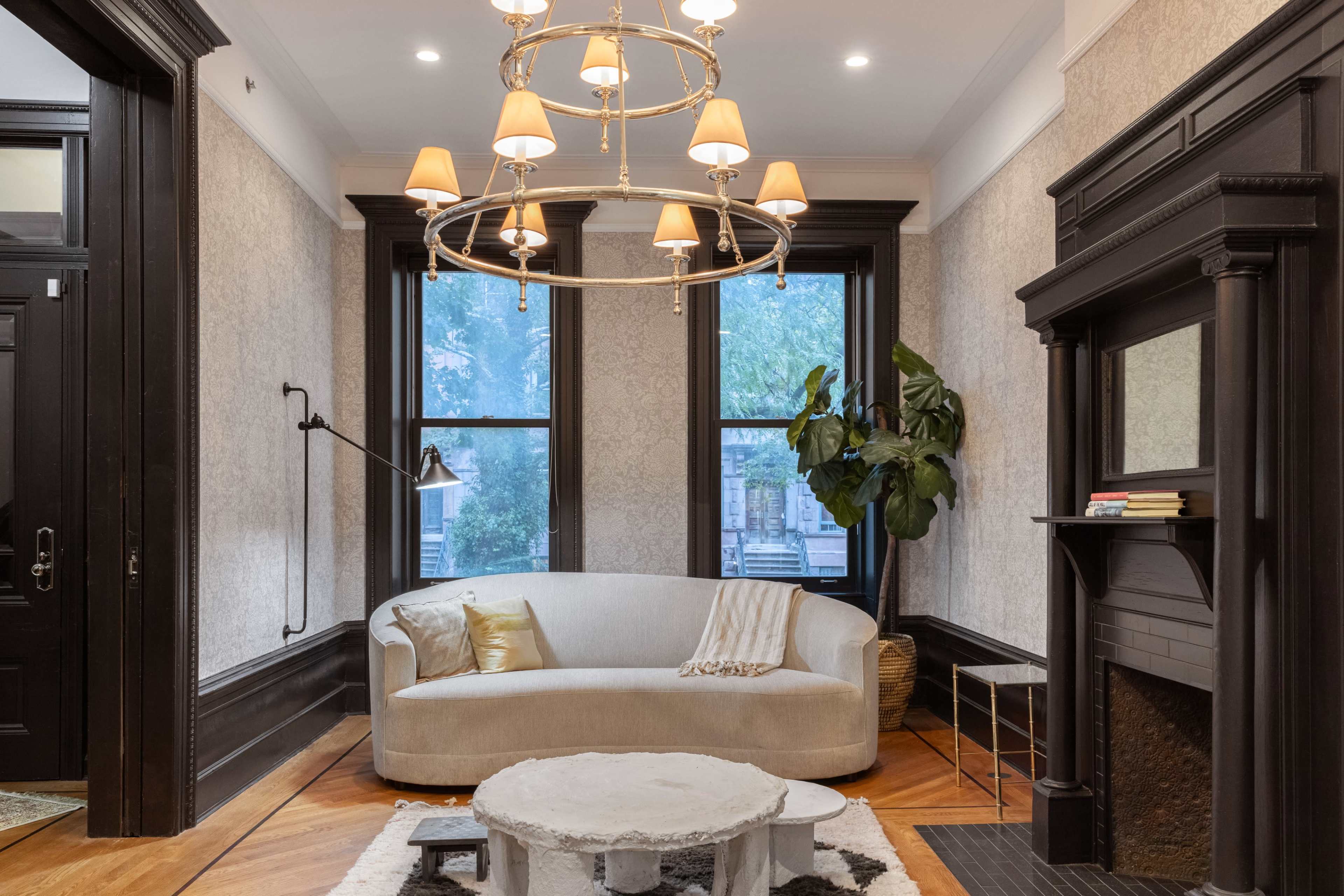 A modern living room with a curved sofa, a round coffee table, large windows, and a decorative fireplace.