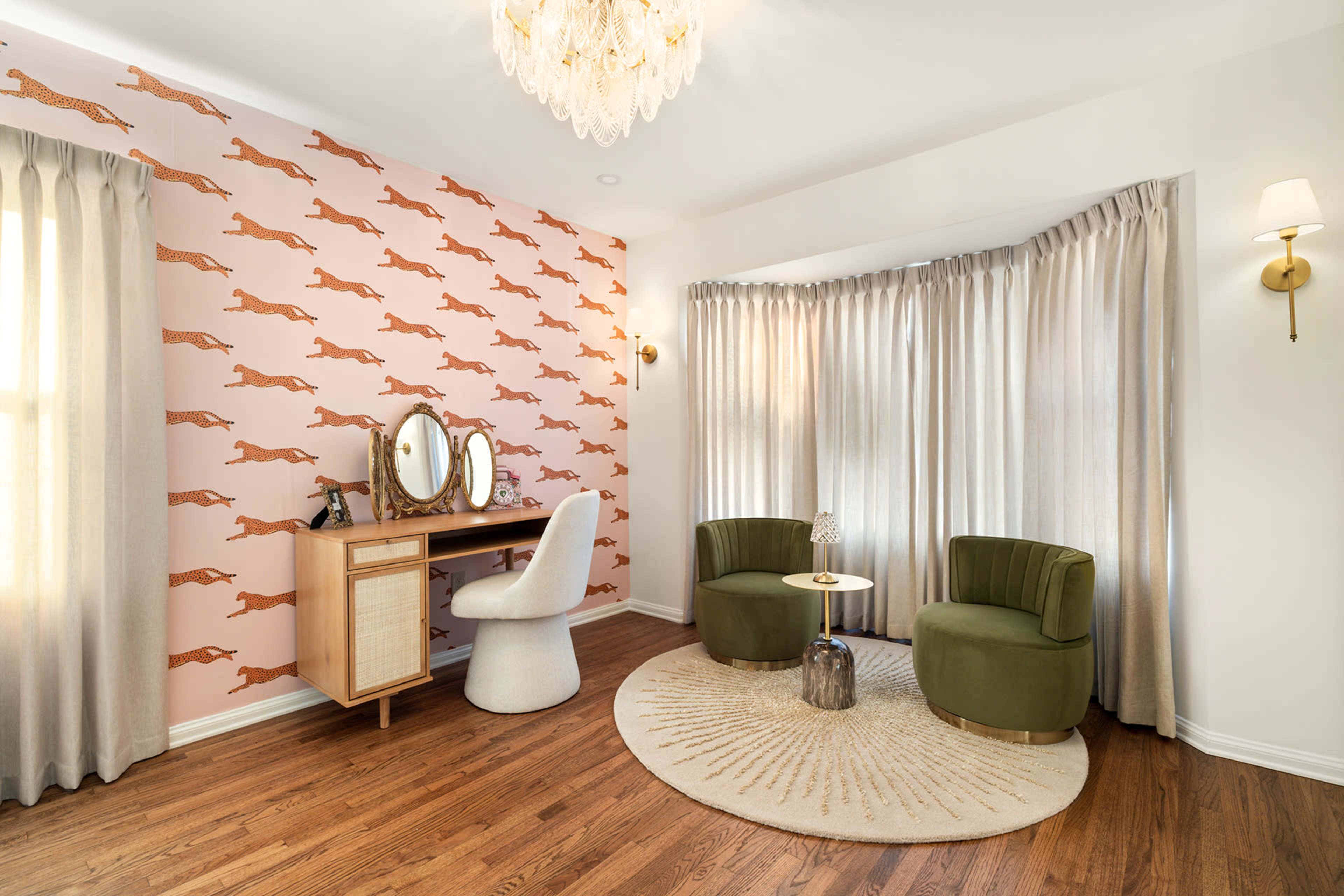 The room features a patterned wall with running dogs, a vanity with a mirror, two round chairs, and large curtains by a window.