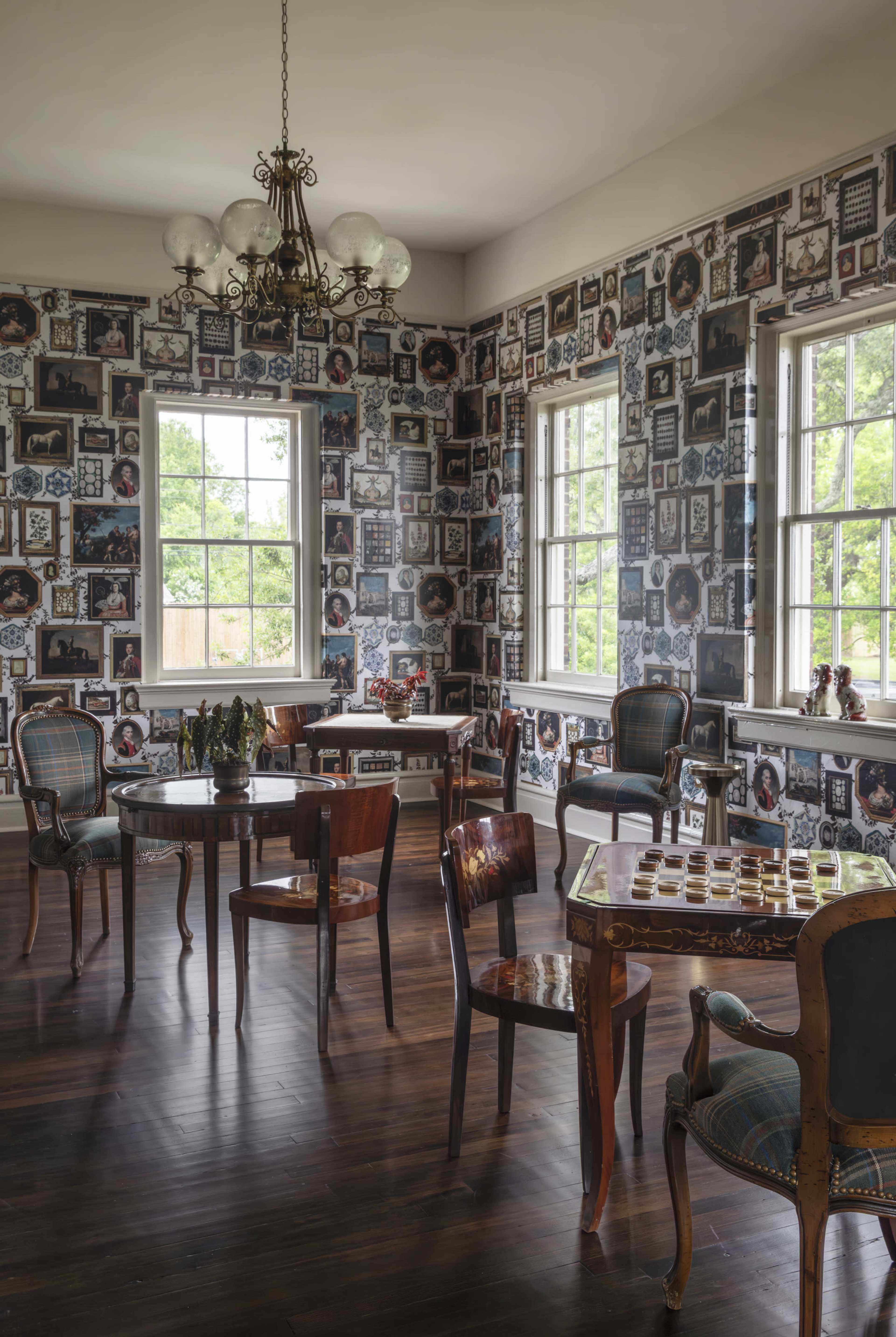 The room features dark wooden flooring and walls covered in a collage of framed photographs, with multiple tables and chairs arranged throughout.