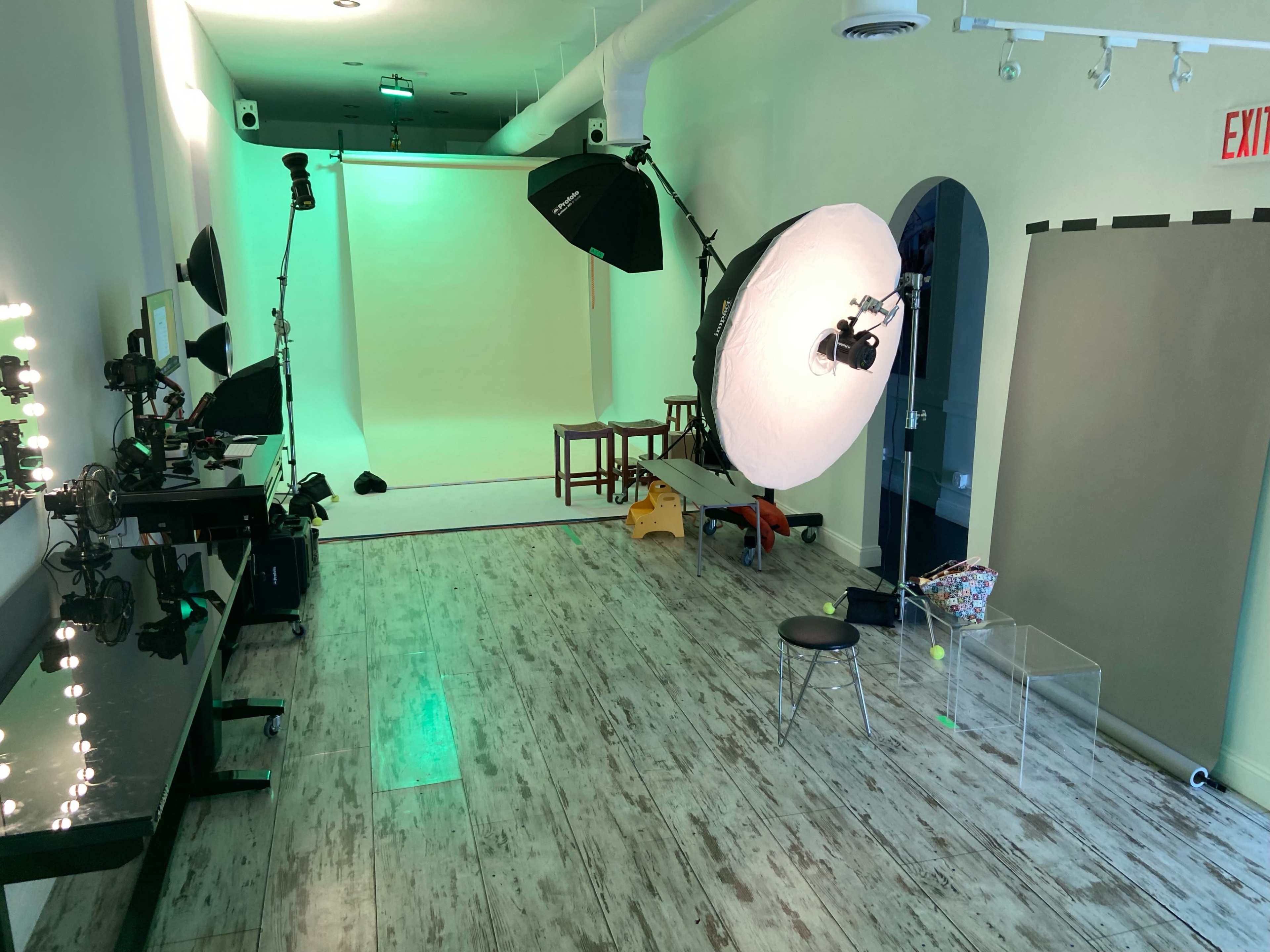 The image shows a spacious photography studio equipped with multiple lights, a backdrop, and various props.