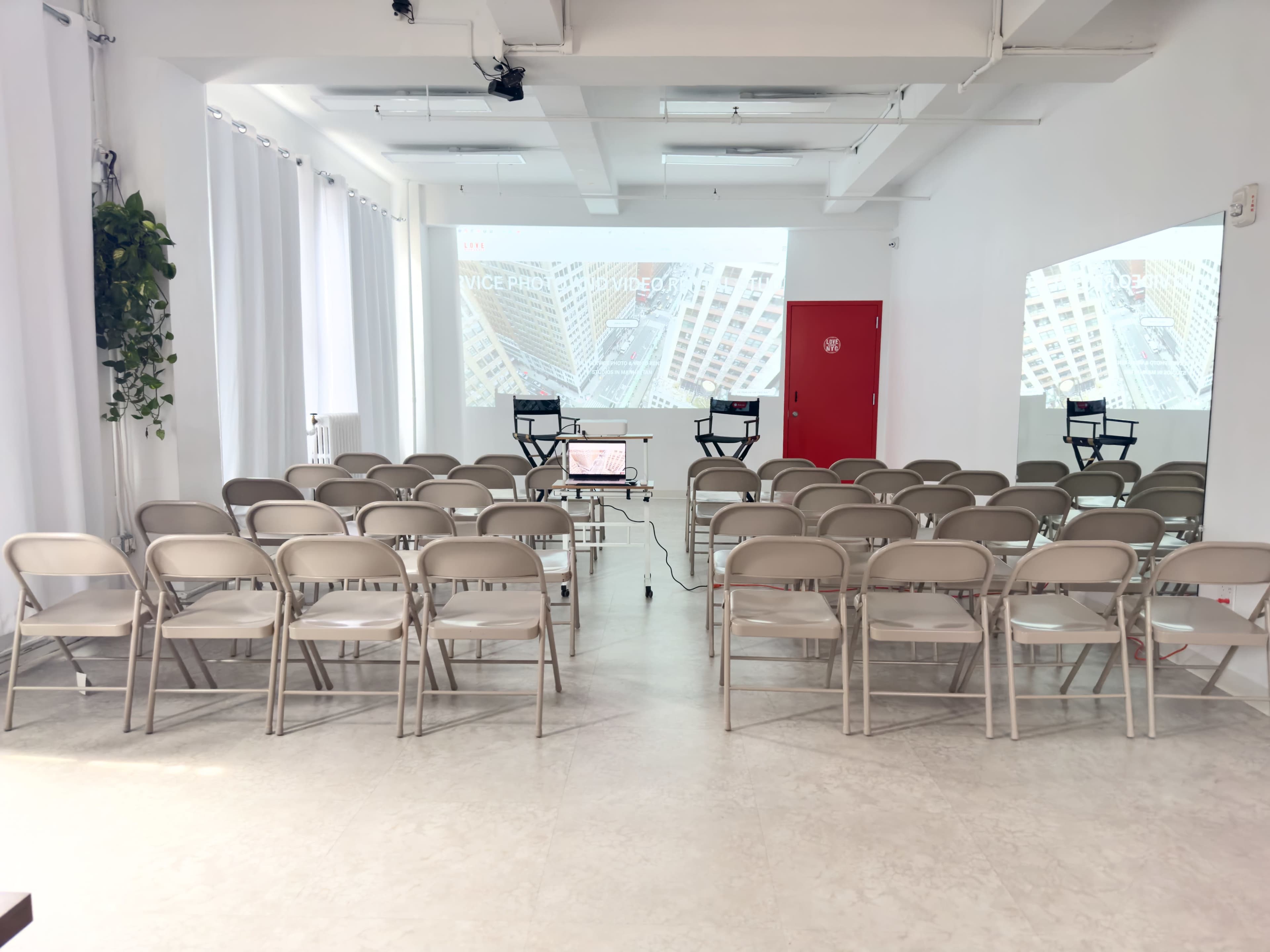 A row of beige chairs faces two screens in a bright, minimalist room set up for a presentation.