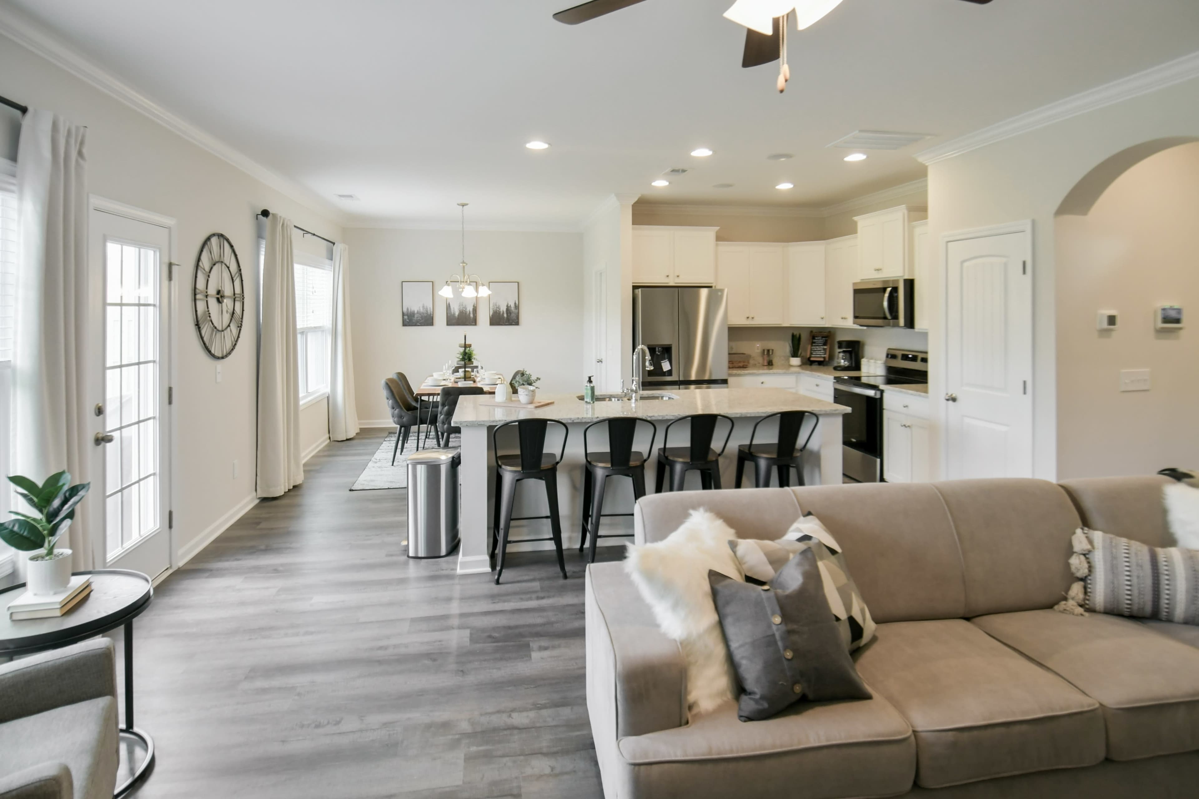 A modern open-concept living space features a kitchen with a large island, dining area, and a cozy seating area with a sofa.