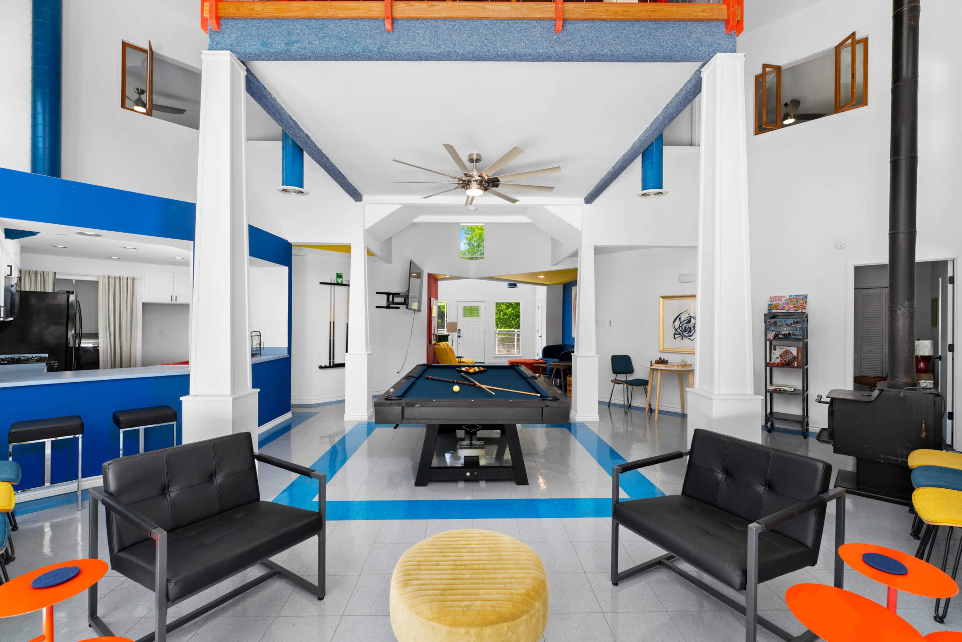 A vibrant game room featuring a pool table at its center, surrounded by stylish seating and modern decor.
