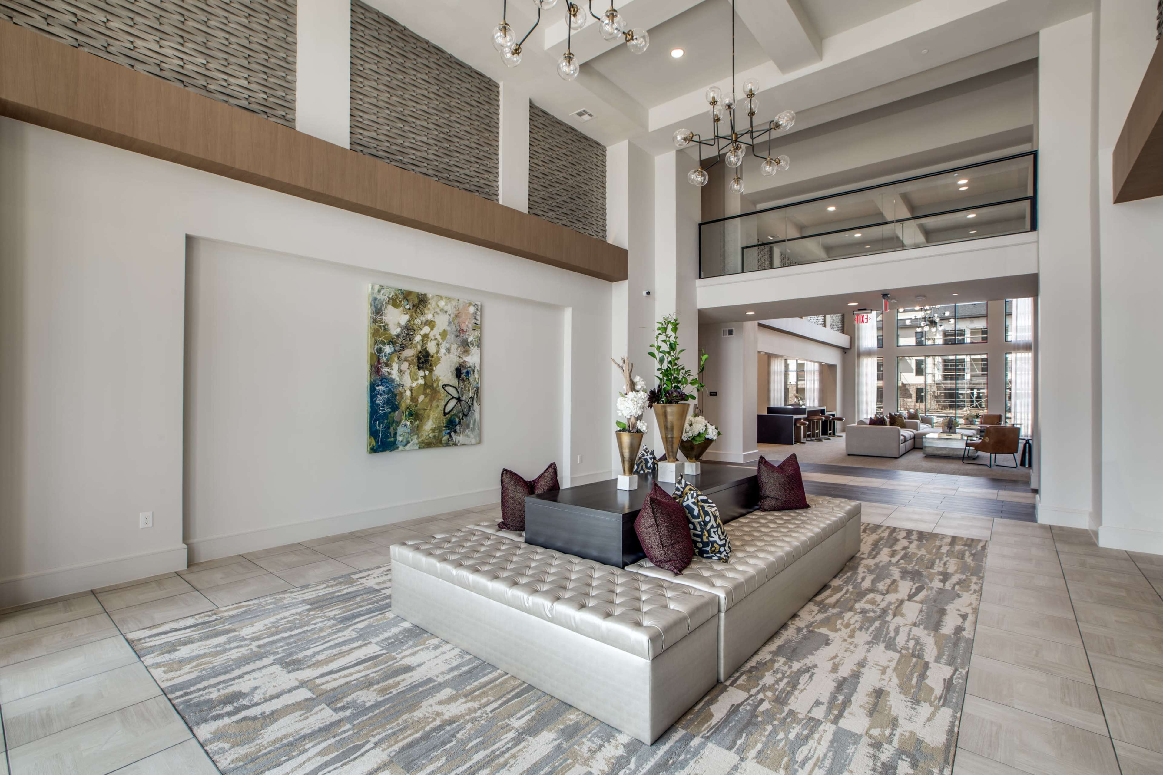 The image shows a modern lobby with a large tufted seating area, decorative artwork on the wall, and stylish fixtures above.