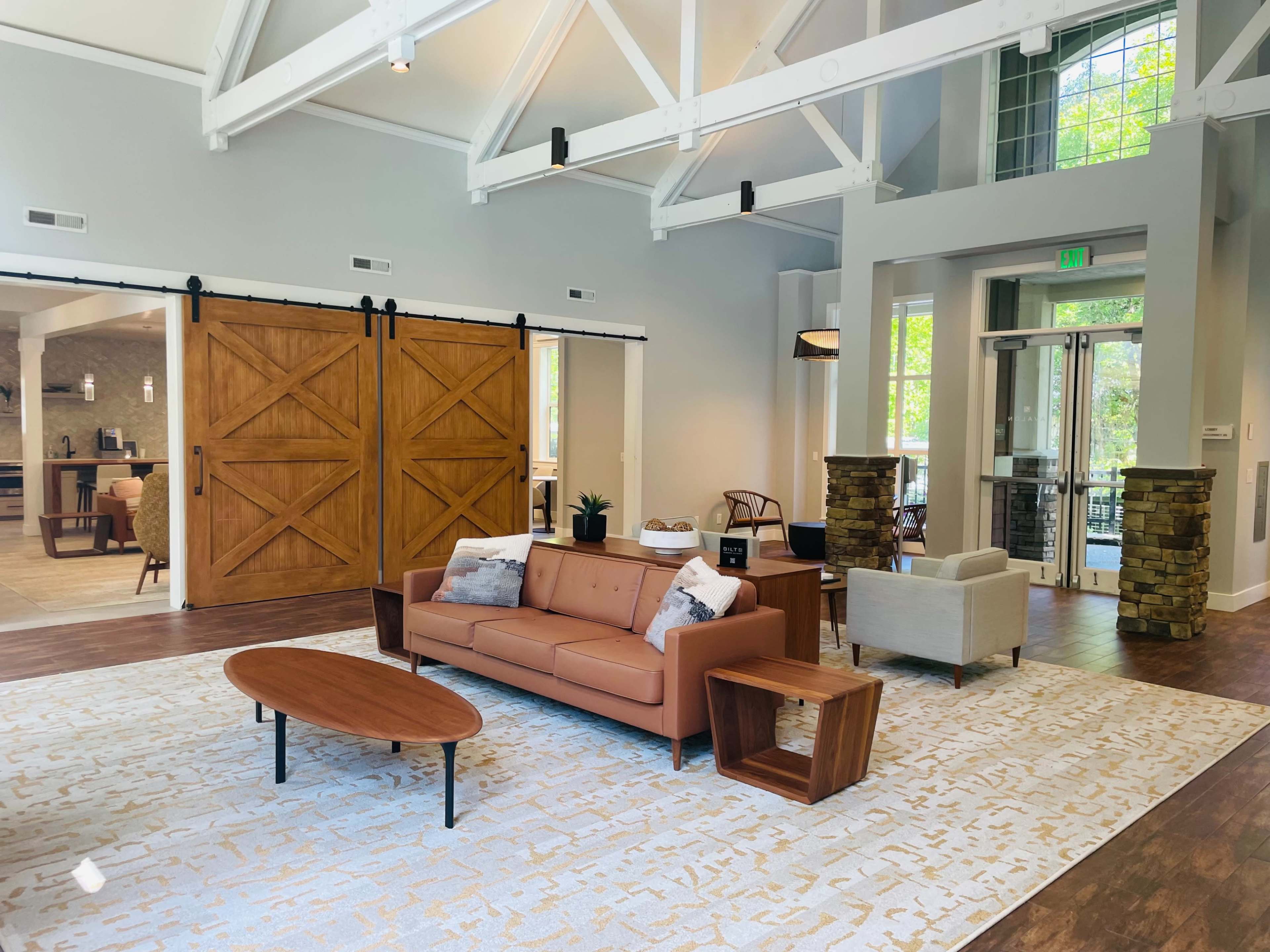 A modern, open-concept lounge area with a brown sofa, coffee table, and a combination of wooden and stone accents.