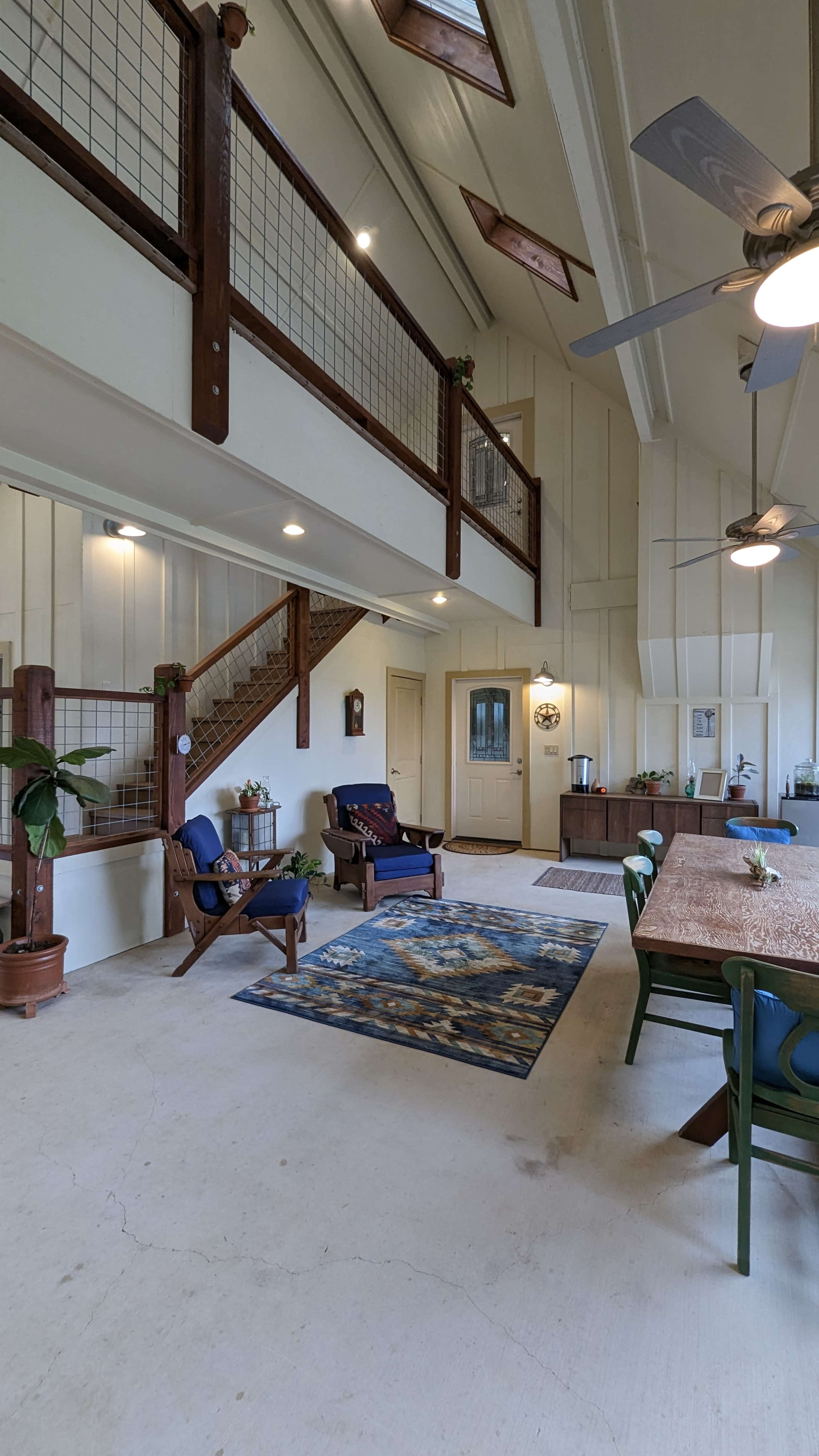 The interior features a spacious, open layout with a dining area, living space, and a staircase leading to a loft.