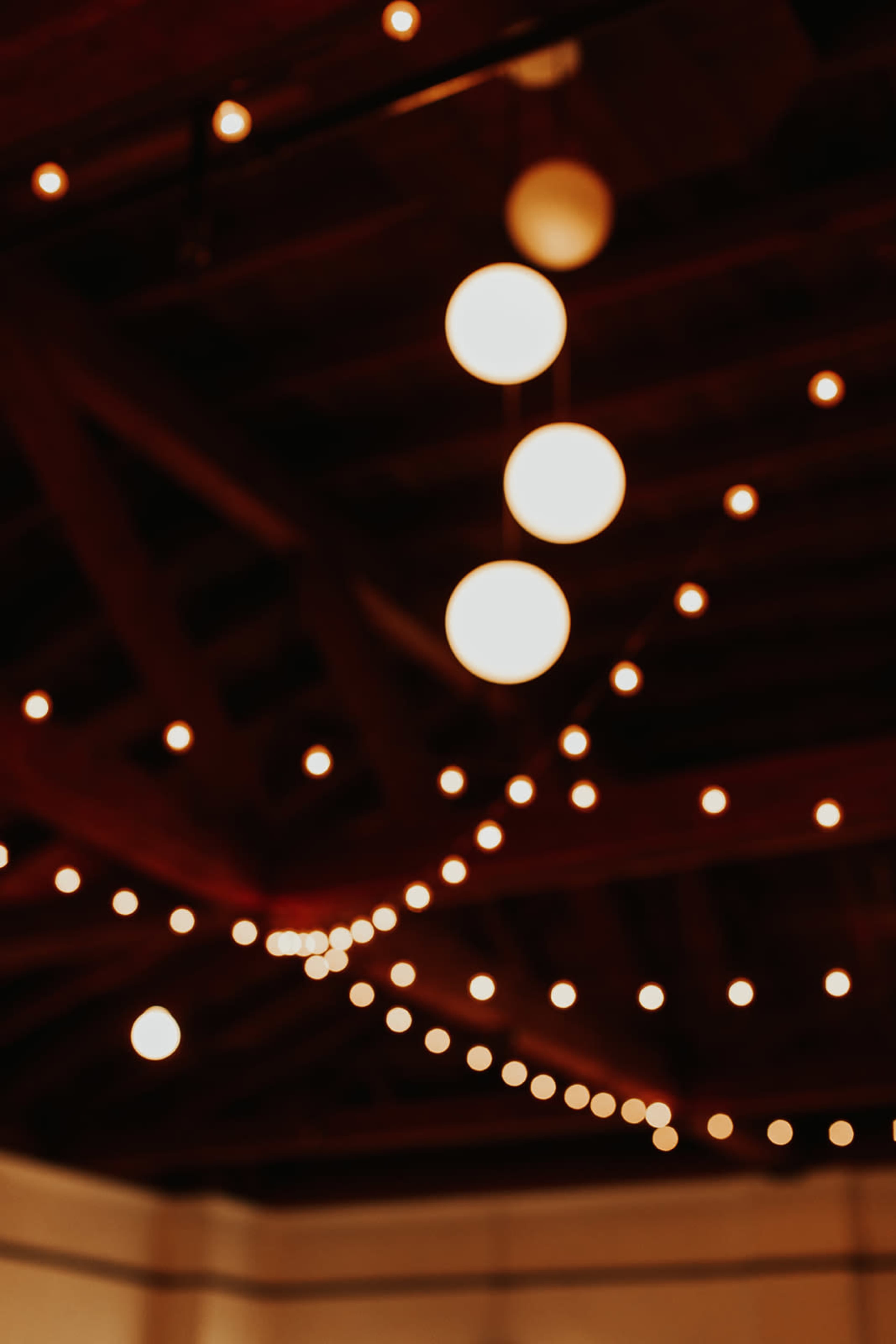 The image shows a blurred view of a ceiling adorned with round pendant lights and string lights.