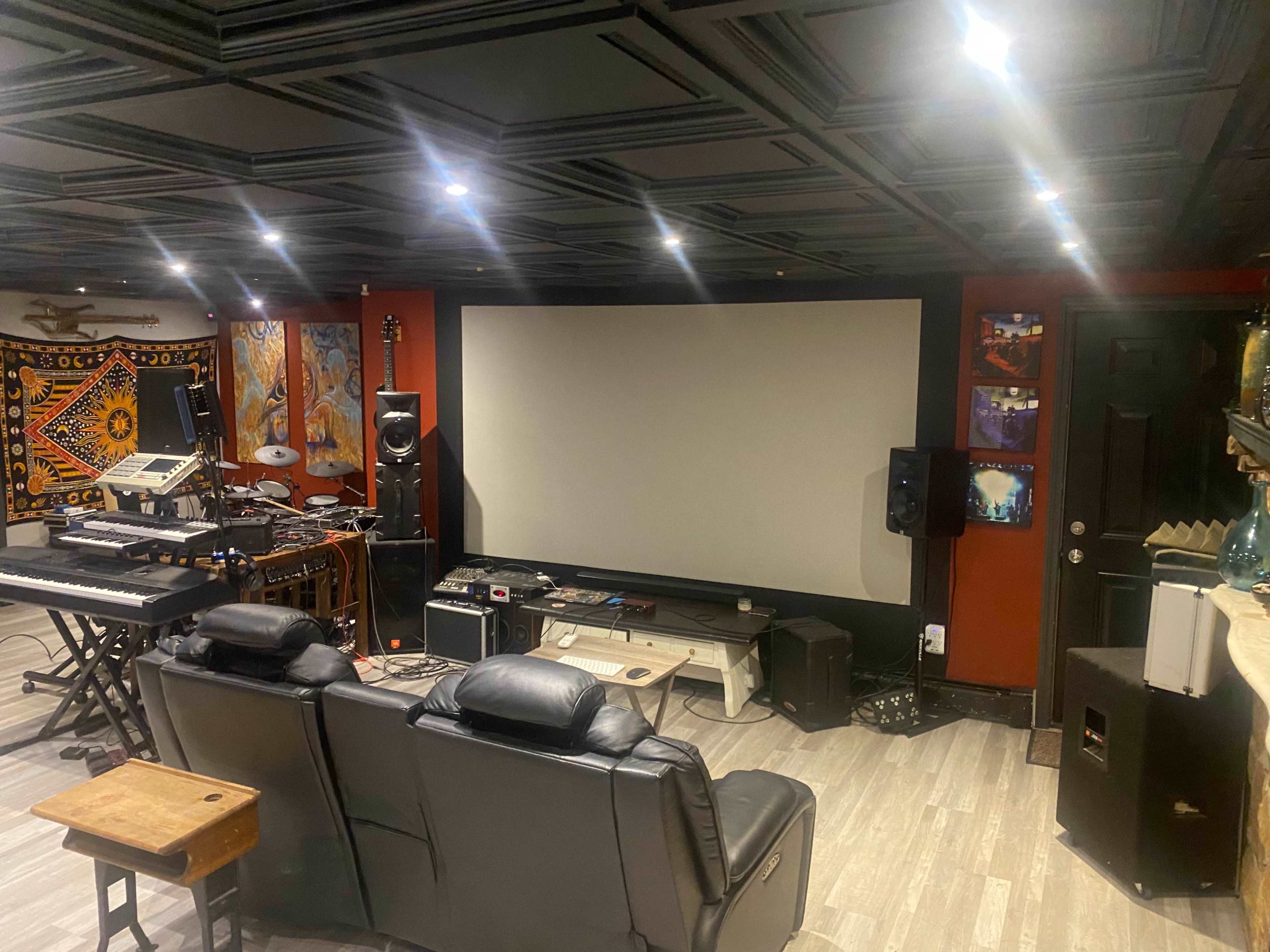 A home theater setup featuring a large projection screen surrounded by audio equipment and seating.