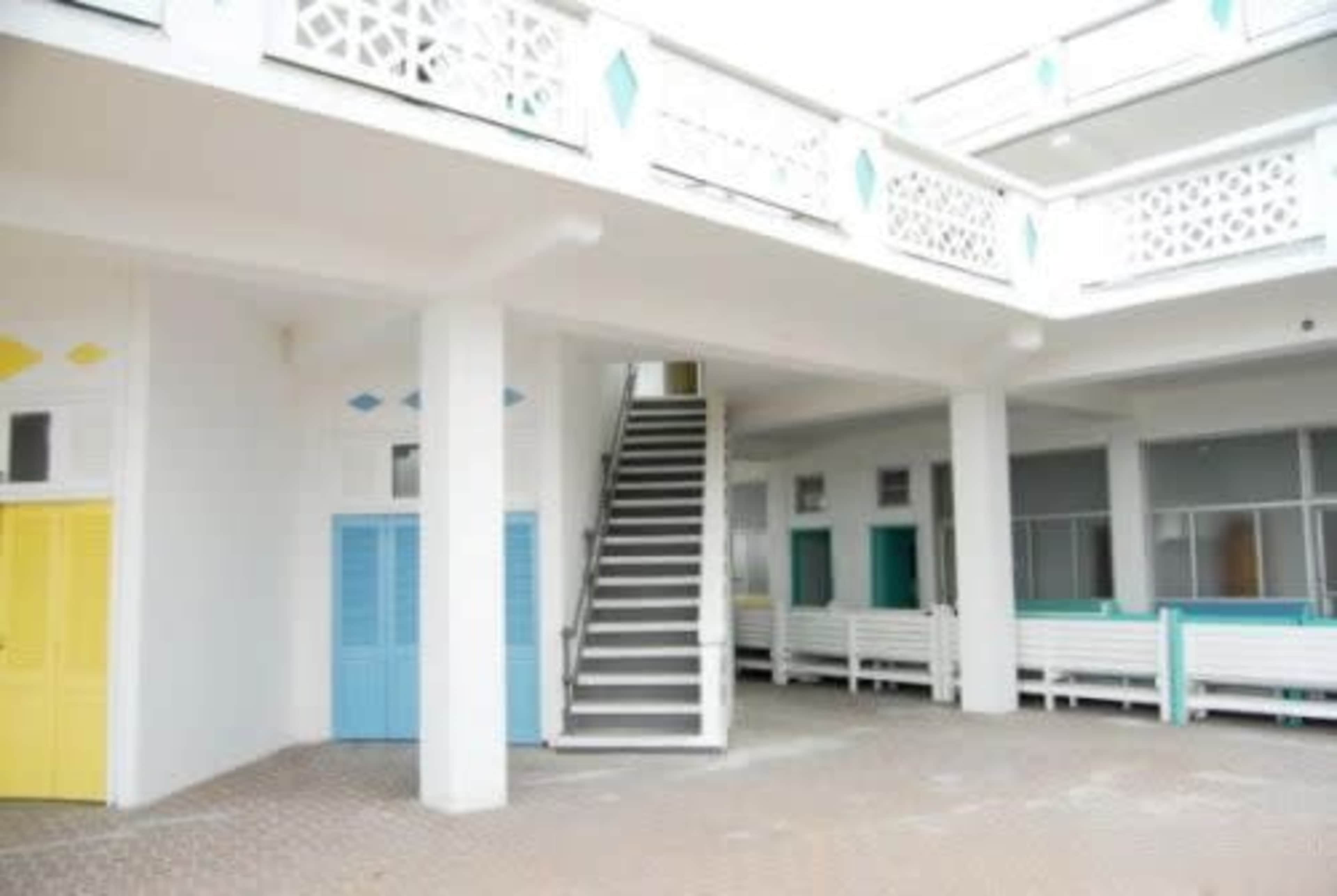 A bright courtyard of a building featuring staircases and colorful doors.