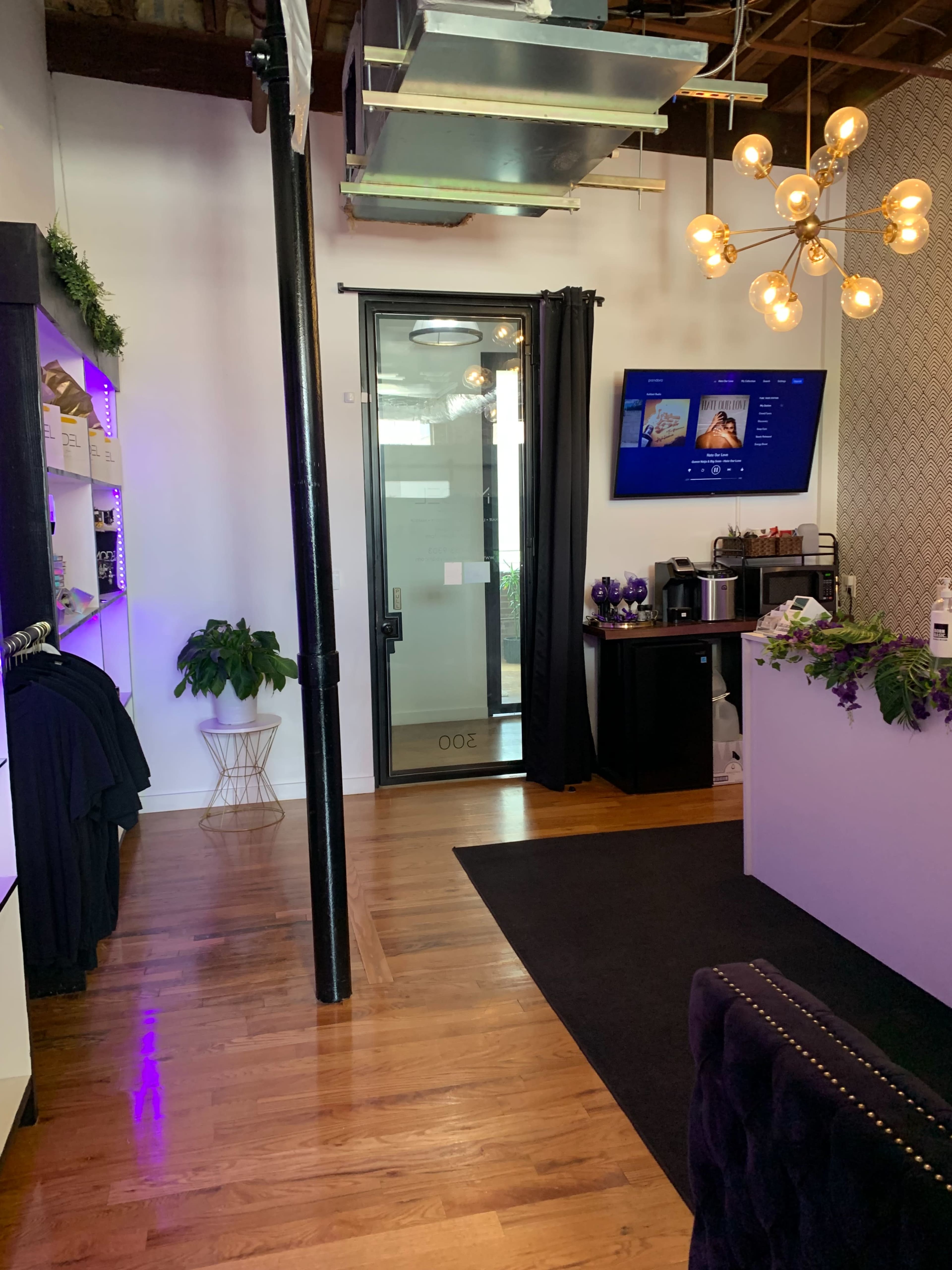 A modern reception area with a dark floor, a large windowed door, and a stylish lighting fixture above a counter.