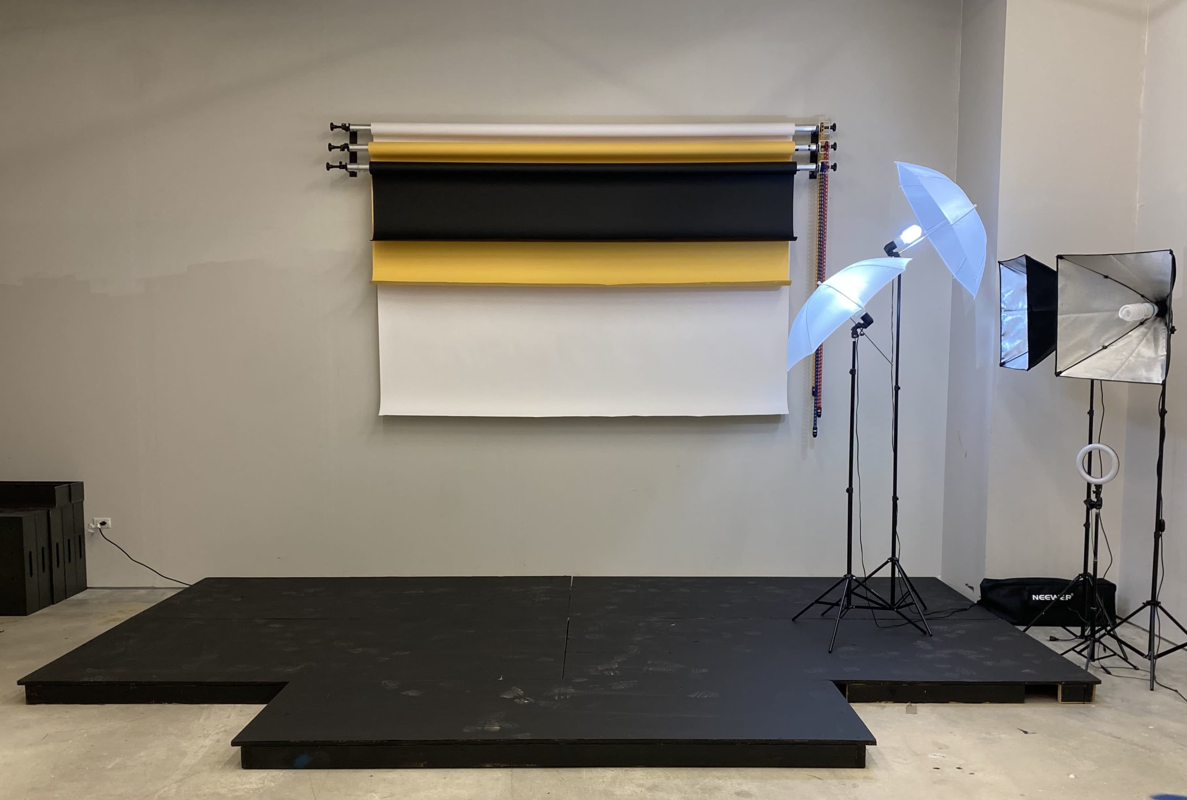 A photography studio setup with a backdrop of colored rolls and several lighting equipment on stands.