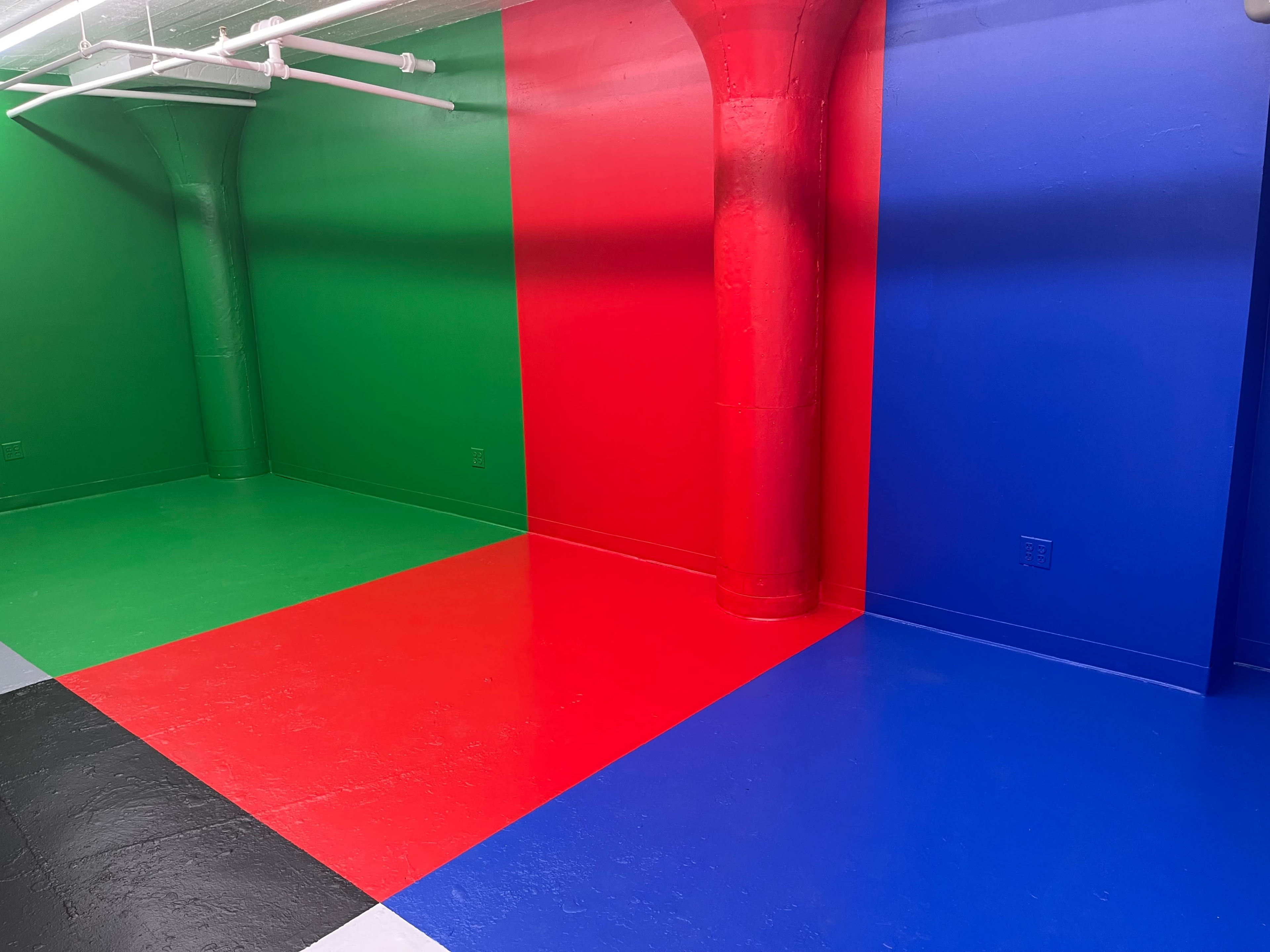 A room with brightly colored walls painted in green, red, and blue sections, along with a black and white floor.