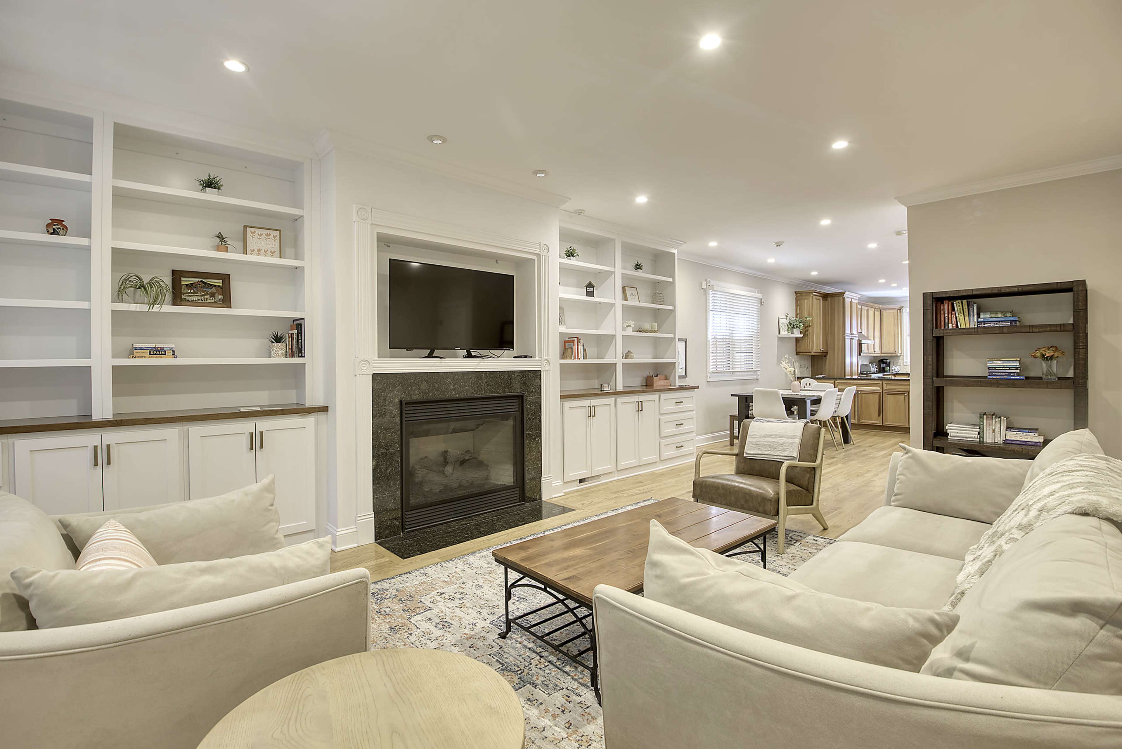 The image shows a cozy living room featuring a fireplace, built-in shelves, and a seating arrangement with sofas and a coffee table.