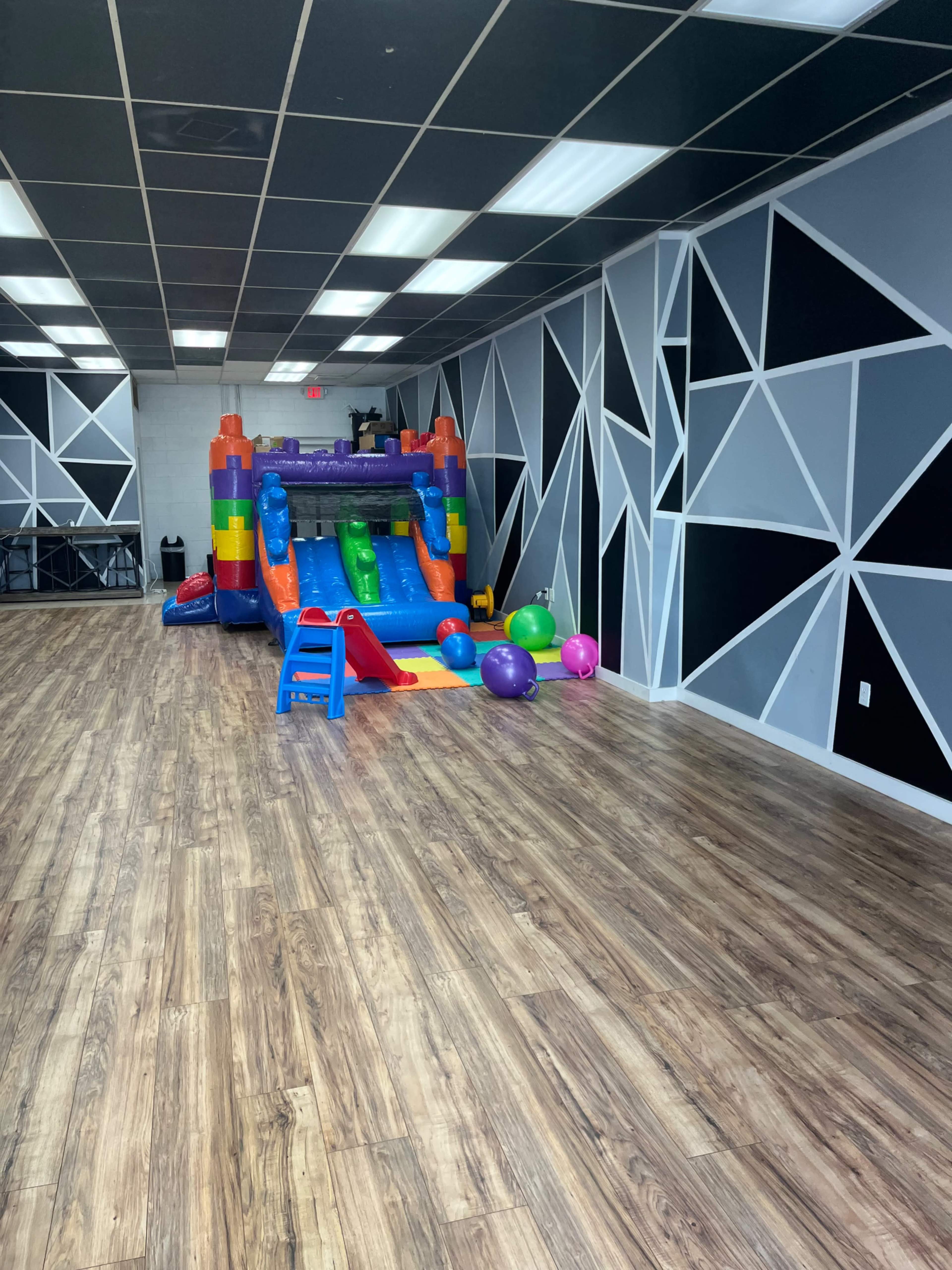 An indoor play area with a colorful inflatable slide and various plastic balls scattered on the floor.