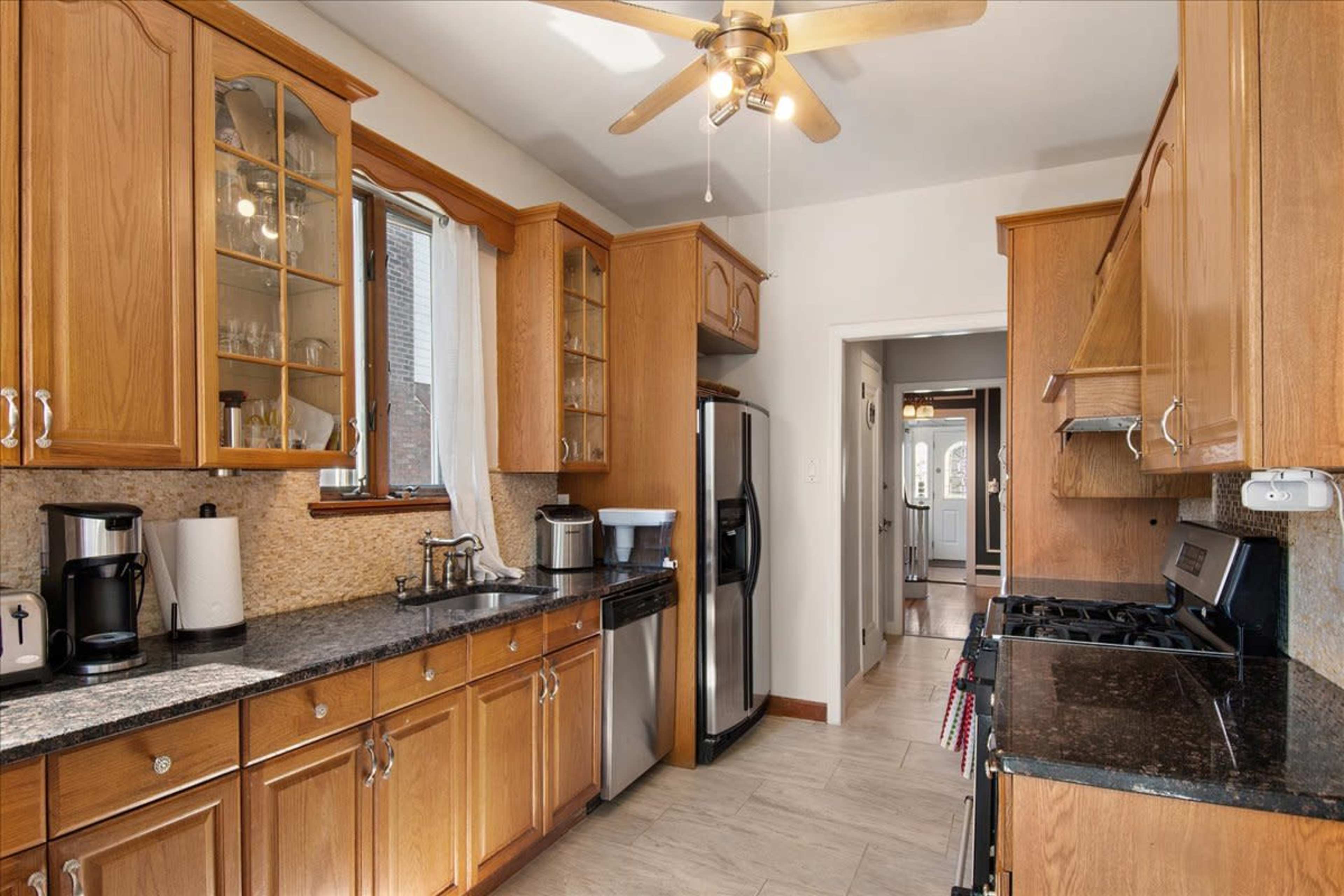 The kitchen features wooden cabinets, a dark granite countertop, and stainless steel appliances.