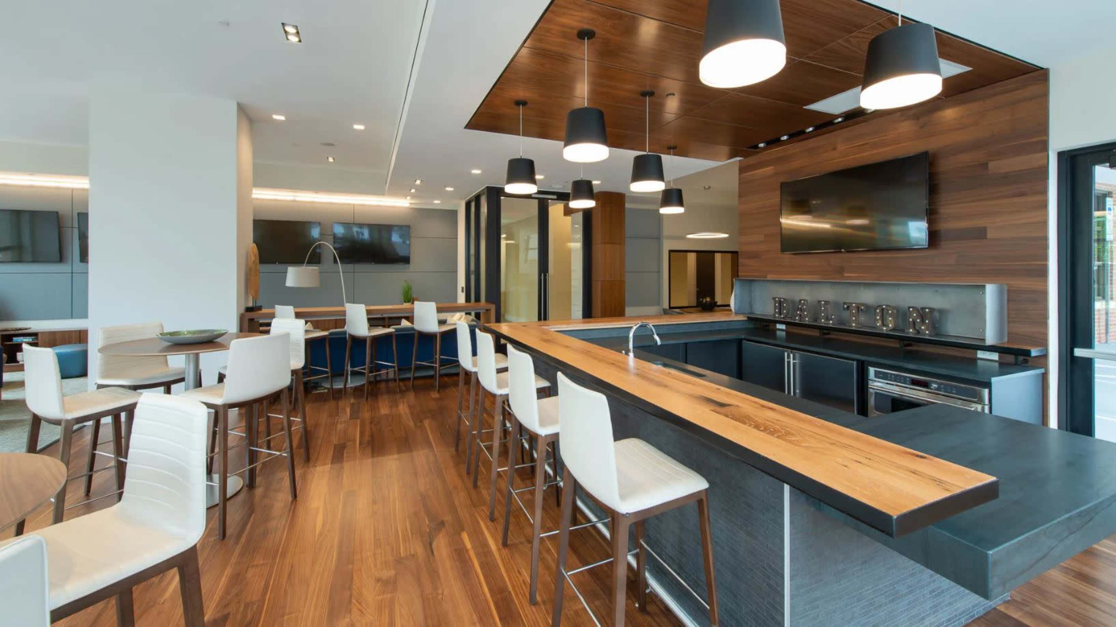 A modern kitchen with a large wooden island, bar stools, and contemporary lighting fixtures.