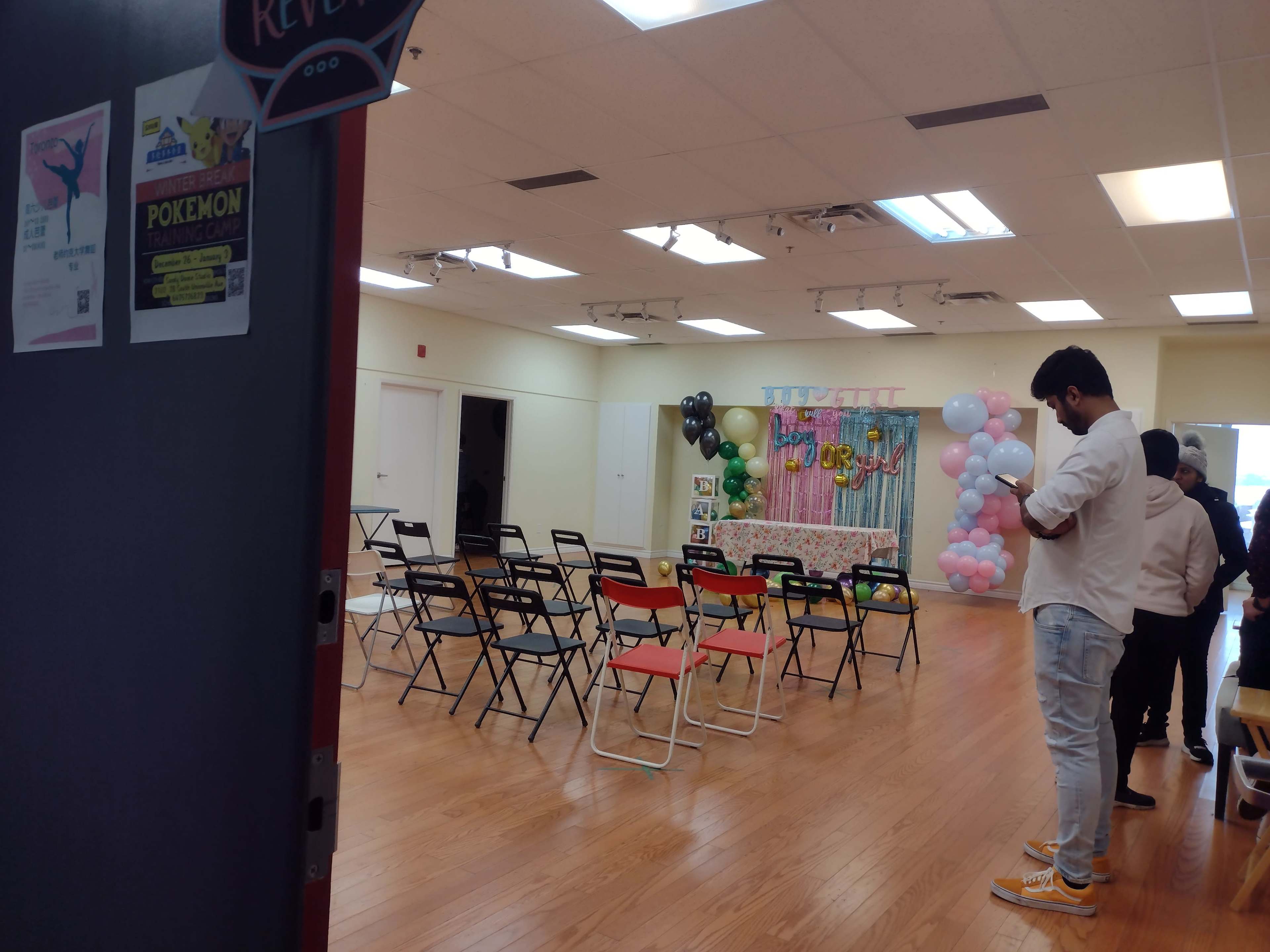An event space set up with rows of chairs, decorative balloons, and a backdrop for a party or gathering.