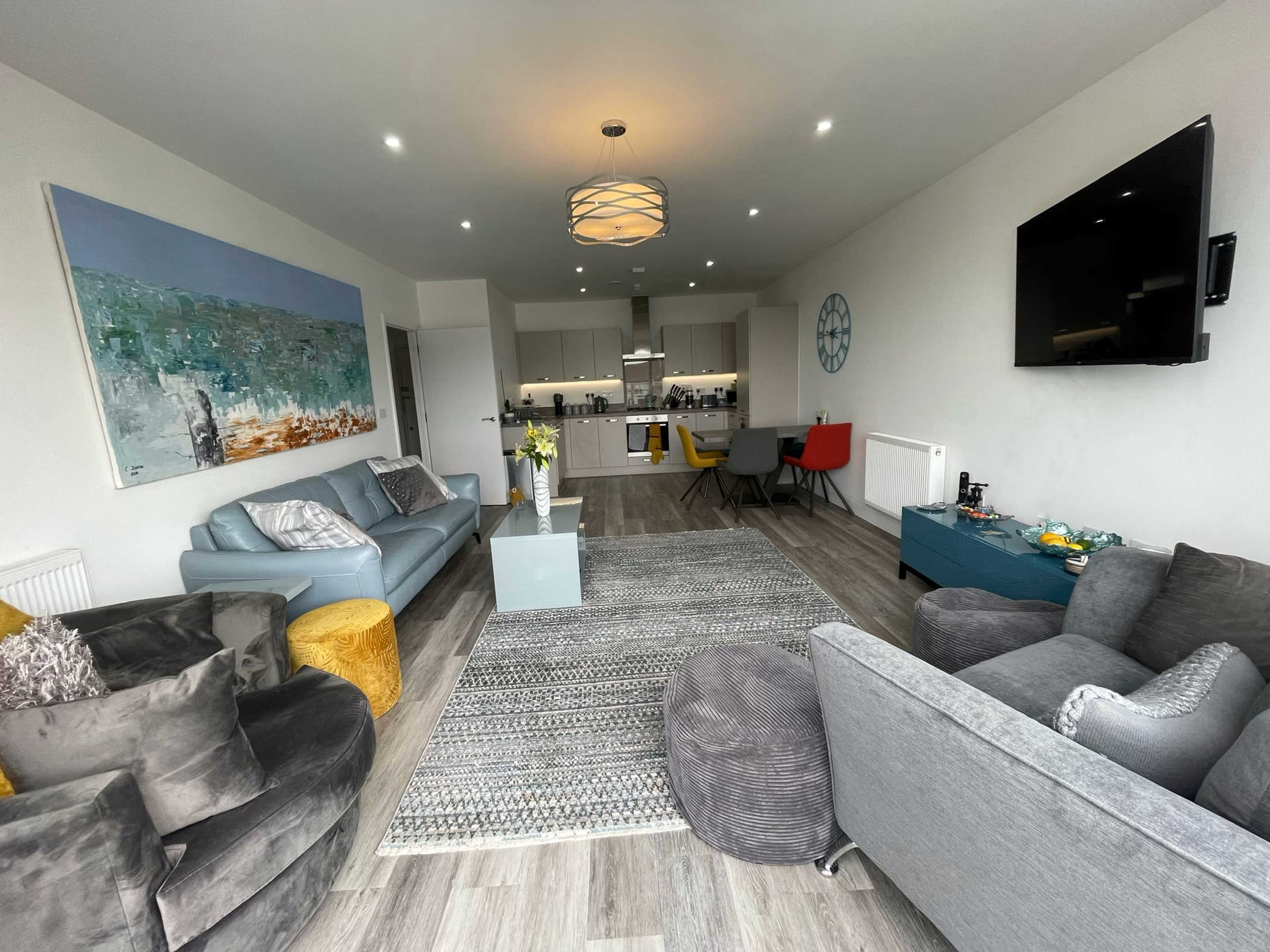 The image depicts a modern living room with a combination of sofas, a coffee table, and a dining area visible in the background.