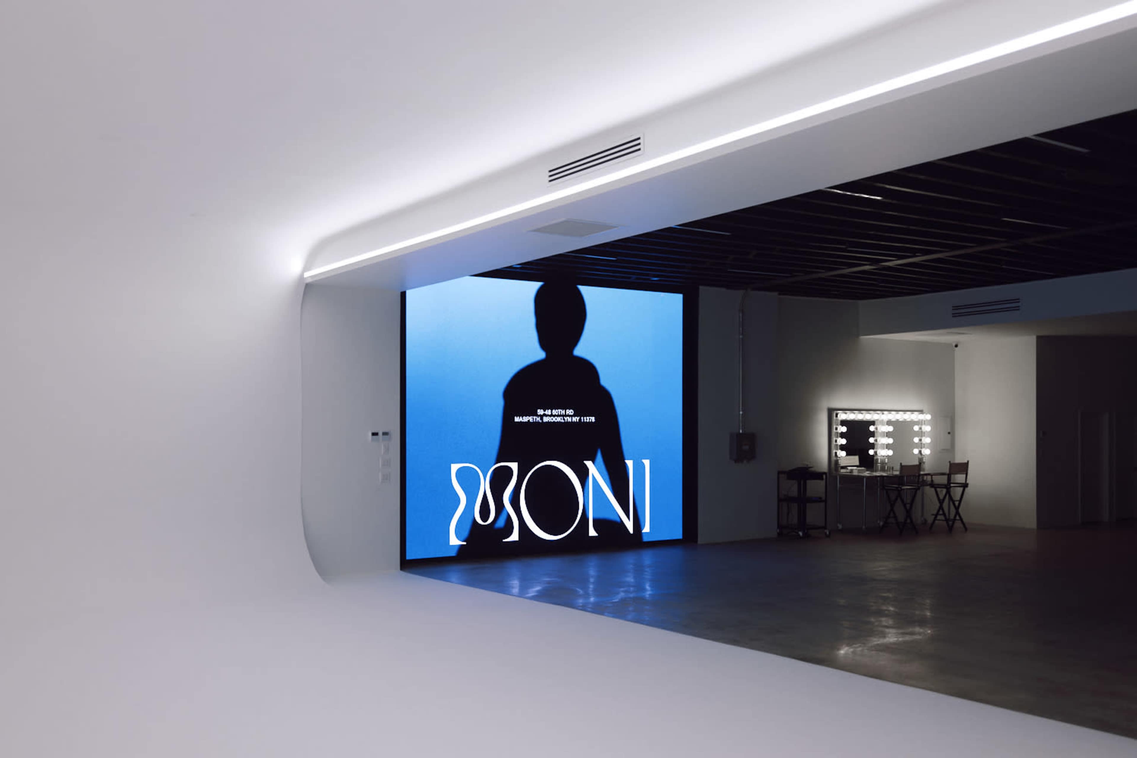 A large screen displays a silhouette against a blue background in a modern, minimalistic studio space.