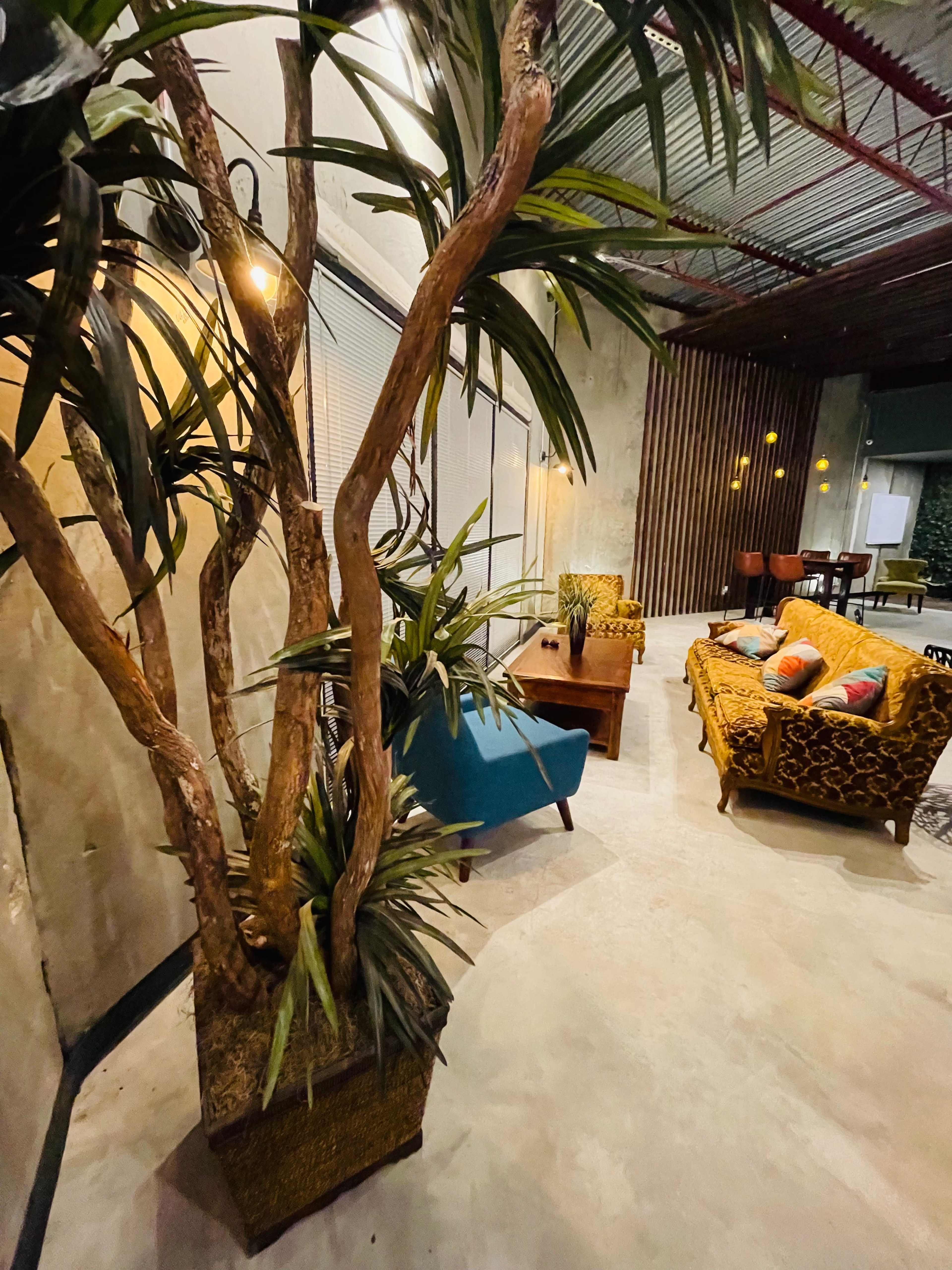 A cozy interior space featuring a brown sofa, a blue chair, a wooden coffee table, and decorative plants.