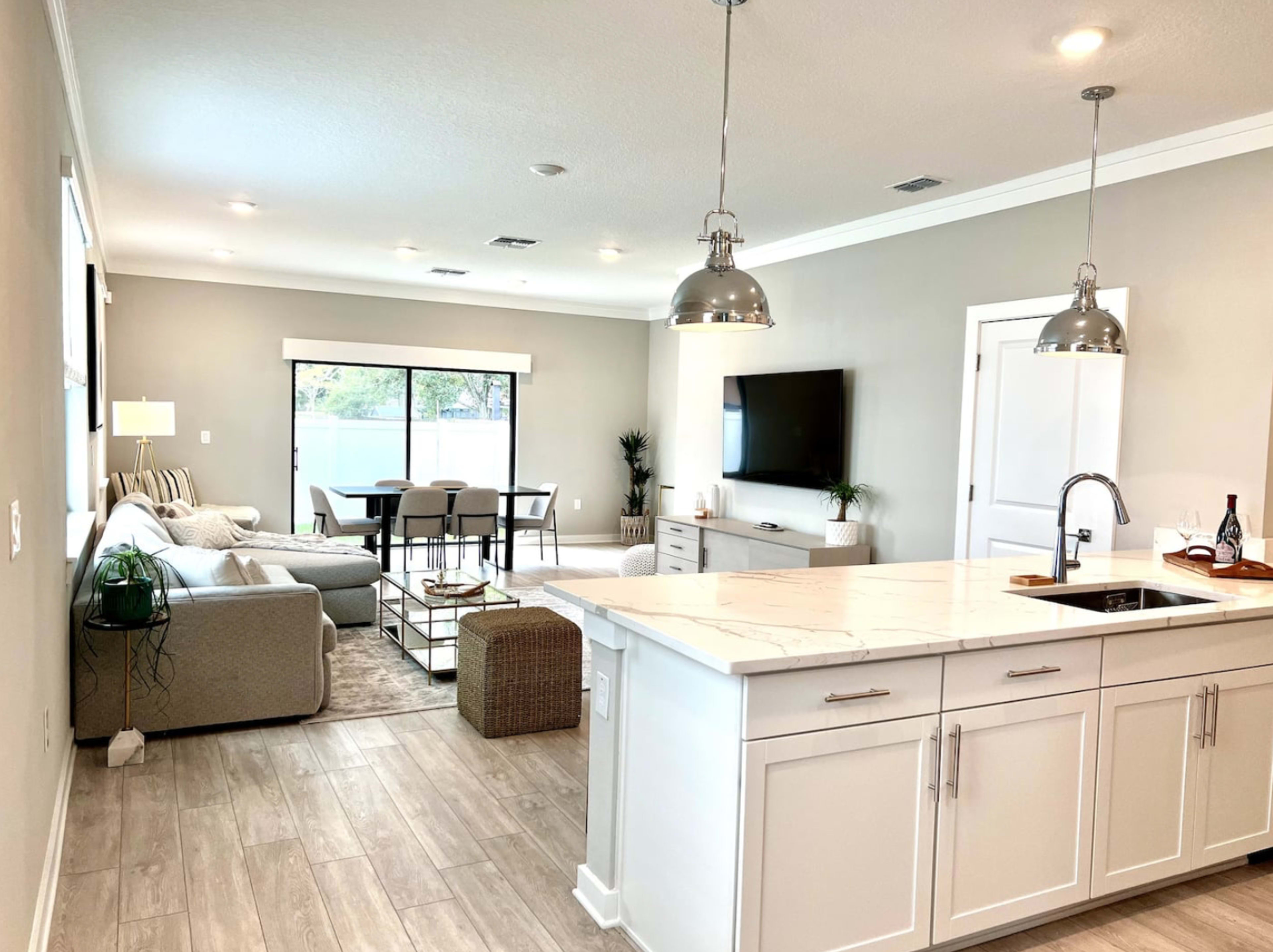 A modern open-concept living space featuring a kitchen island, a dining area, and a cozy seating area with large windows.