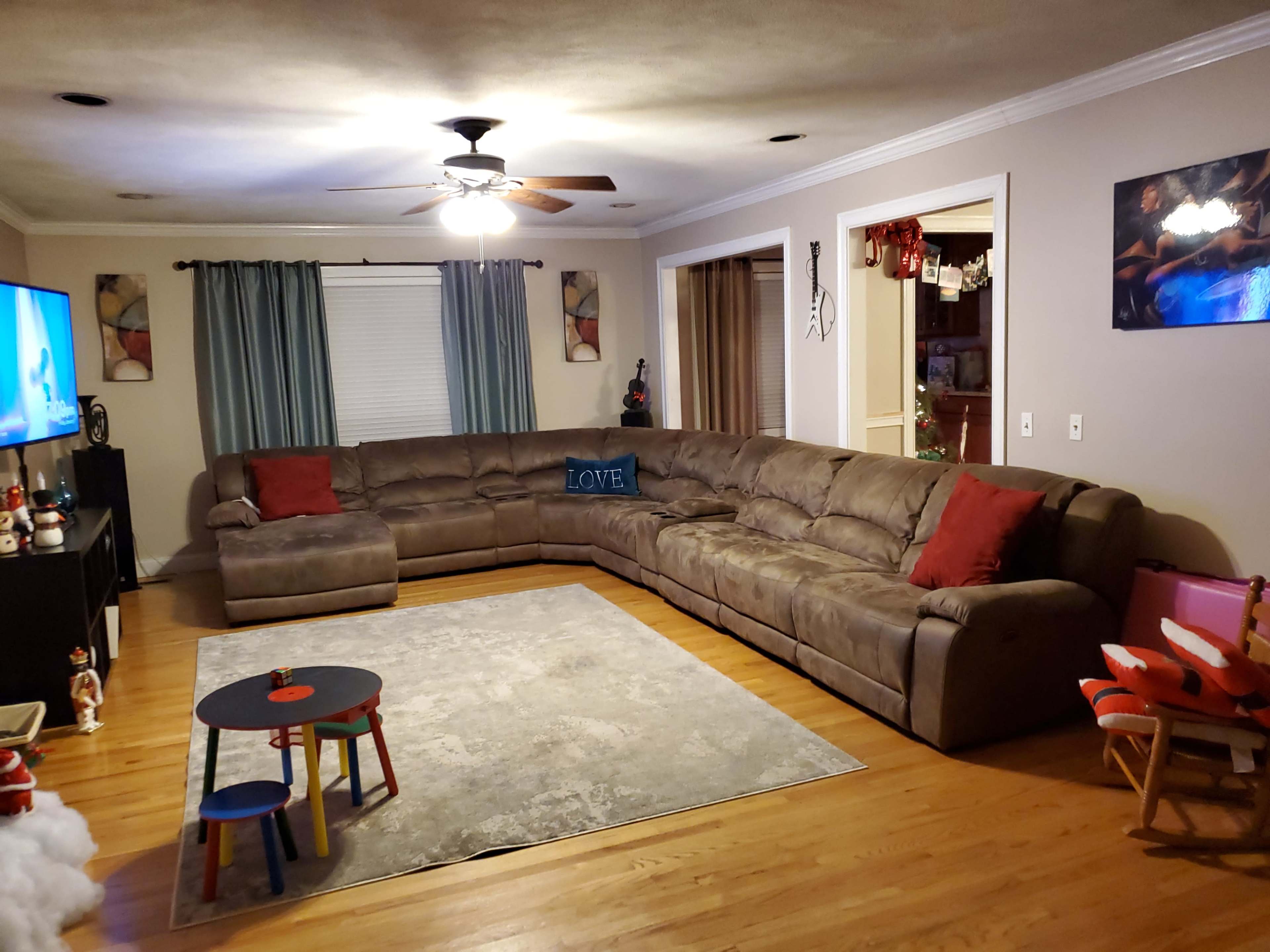 A spacious living room features a large sectional sofa, a low coffee table, and a television set against the wall.